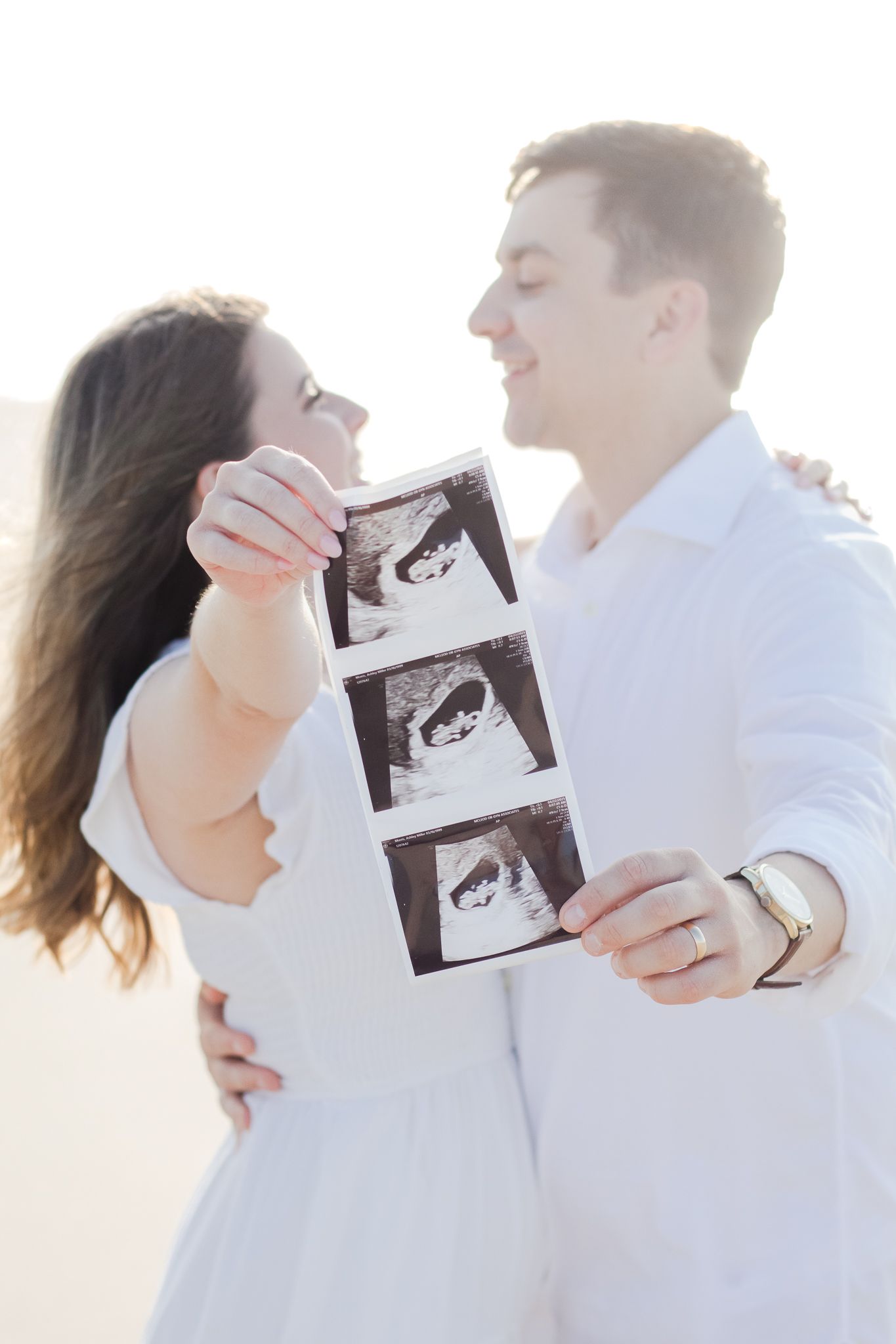 Couple posing for a South Carolina photographer in Huntington Beach State Park on the beach for pregnancy announcement photos portraits.