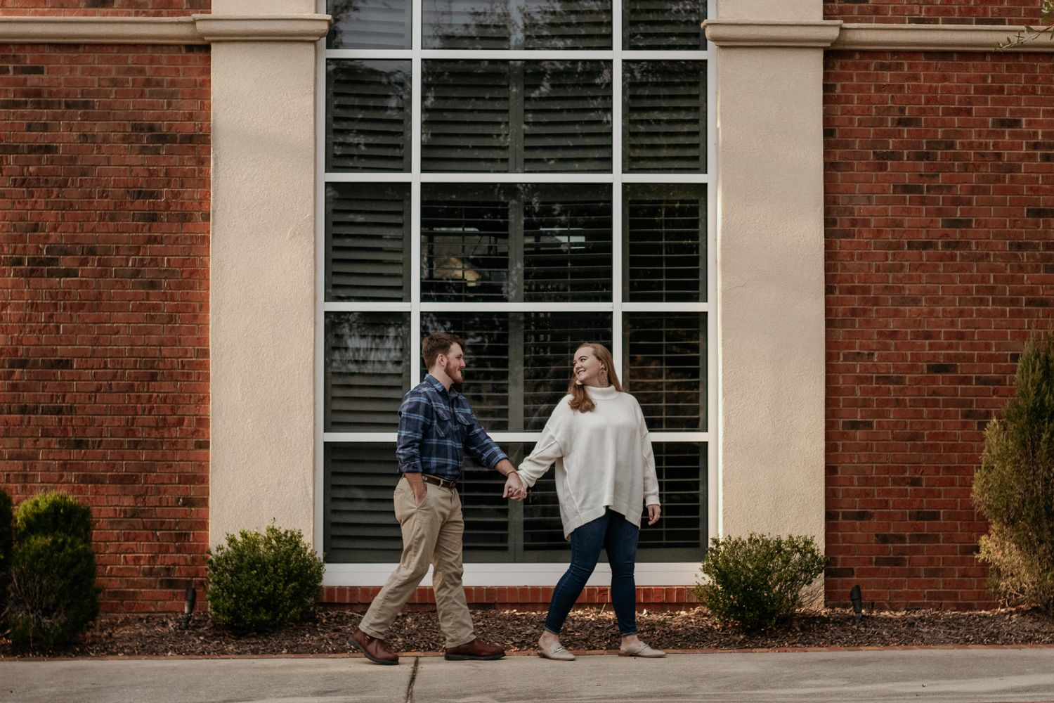 Couple posing for South Carolina photographer in downtown Hartsville SC in Florence engagement portraits photoshoot. Candid true to color