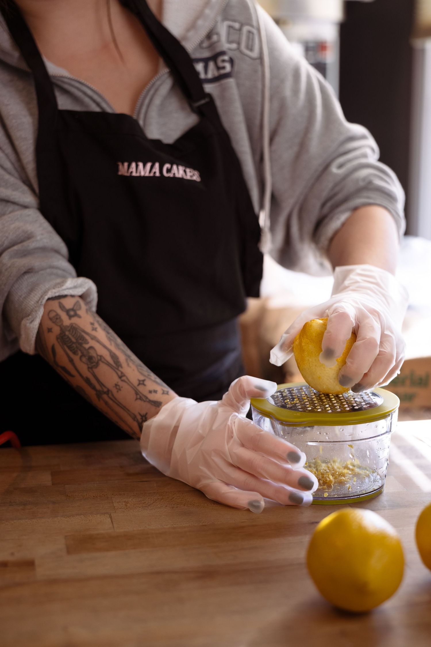 A sequence showing hands wearing gloves zesting a lemon against a grater in a professional kitchen setting.