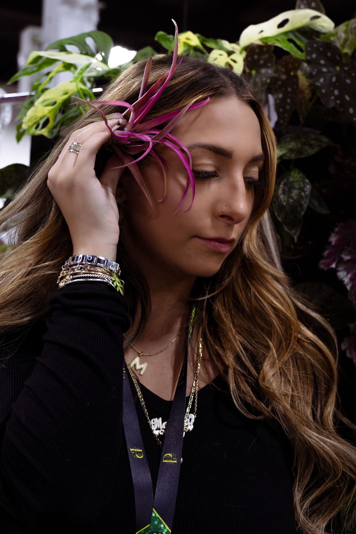 A person with long wavy hair wearing a black hoodie and floral crown poses in a series of artistic profile shots.