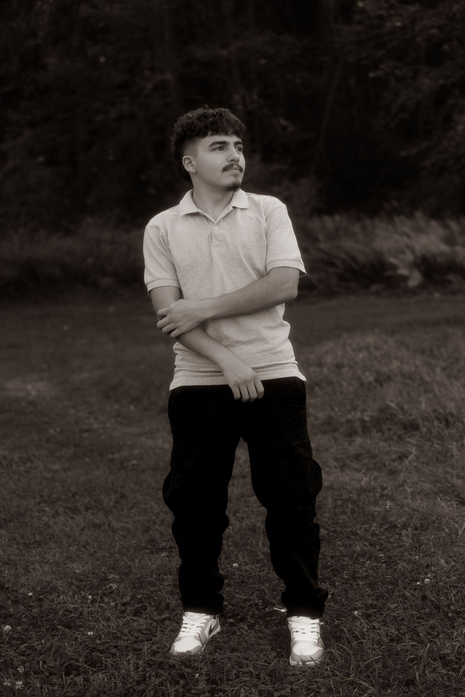 Black and white photo series showing someone sitting on grass wearing casual clothes and white sneakers.