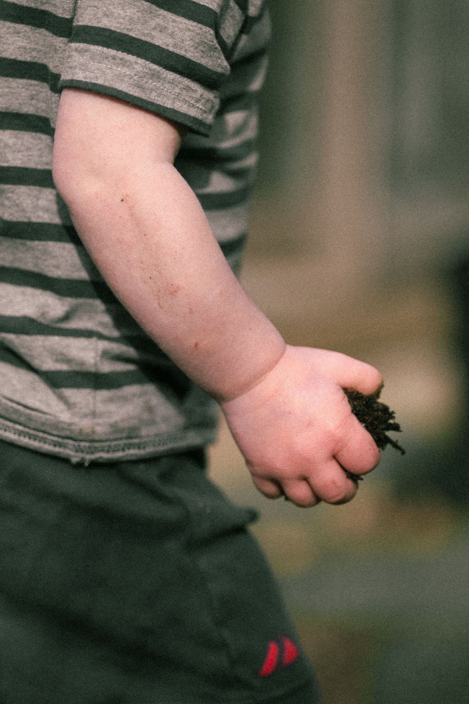 Close-up sequence of a small child's hand holding and examining a tiny object against a blurred background.