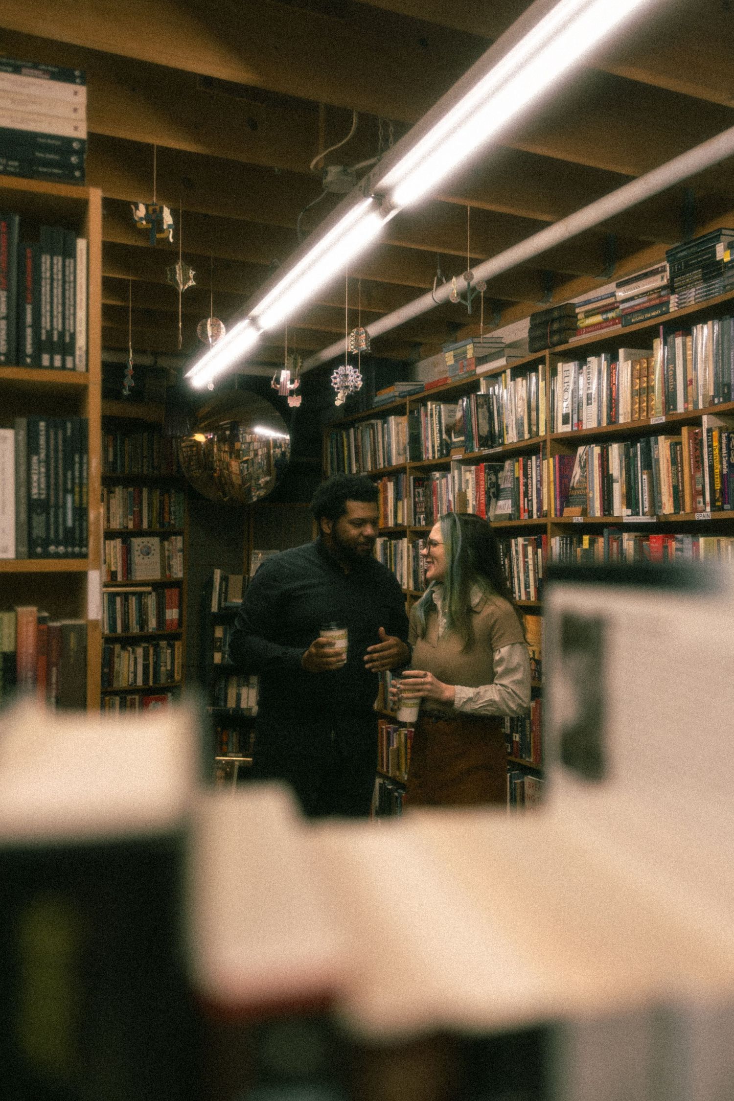 A panoramic view of a dimly lit library or bookstore interior with wooden bookshelves and fluorescent lighting.