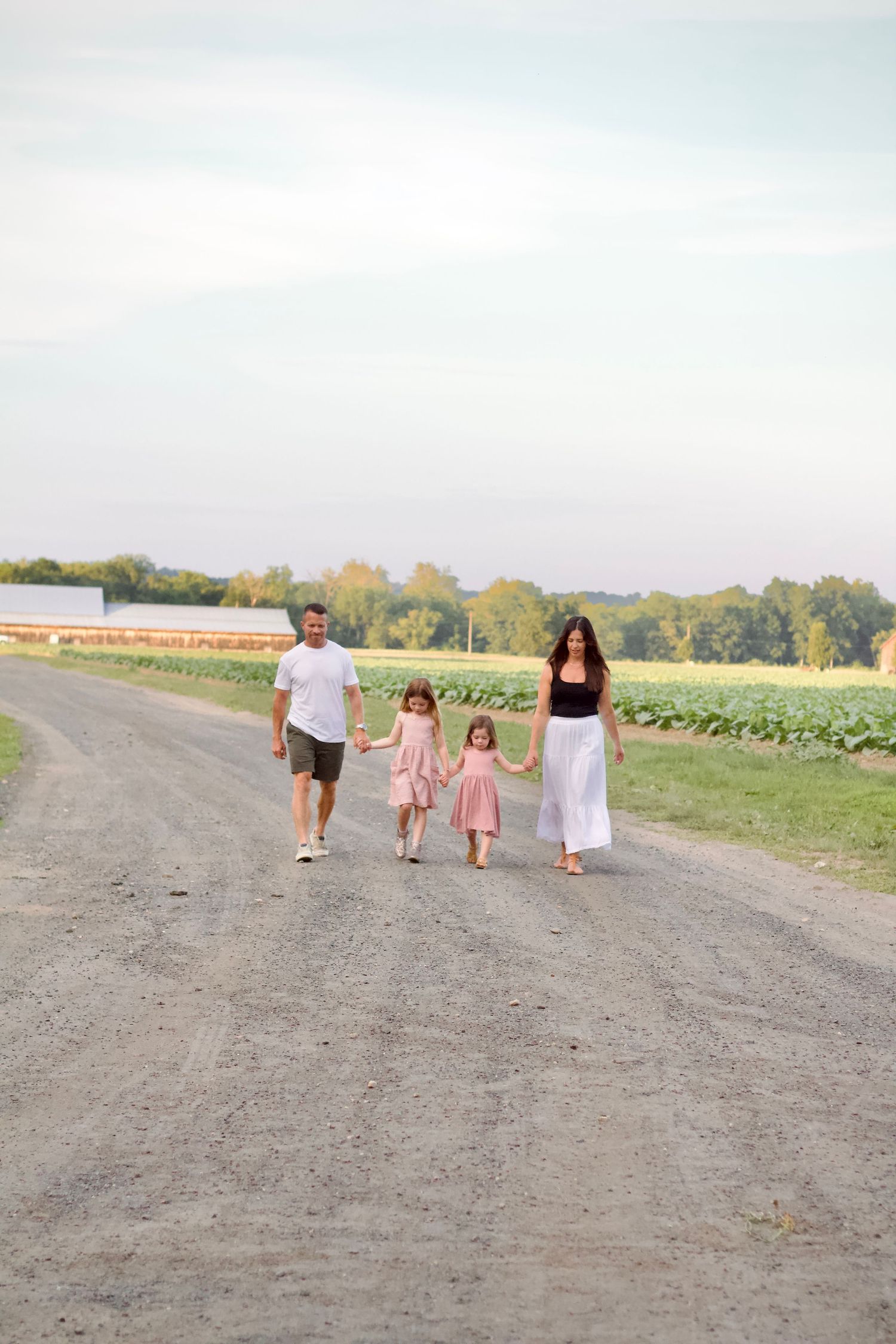 Local Westfield family photographer photo of family Walking along dirt path through agricultural fields on overcast day.