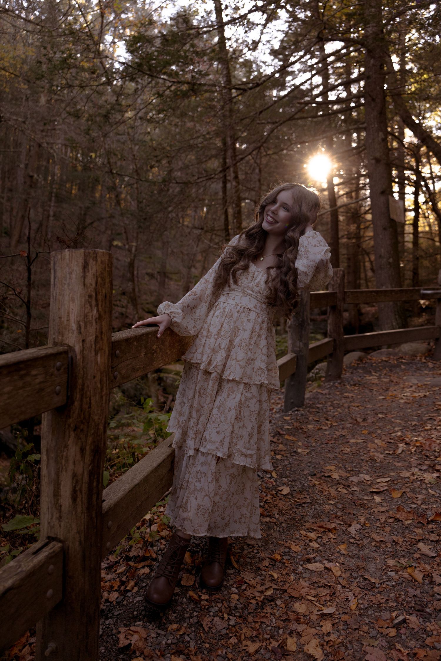 A dreamy vintage-style scene in the woods with a layered white lace dress against a rustic wooden fence at sunset.