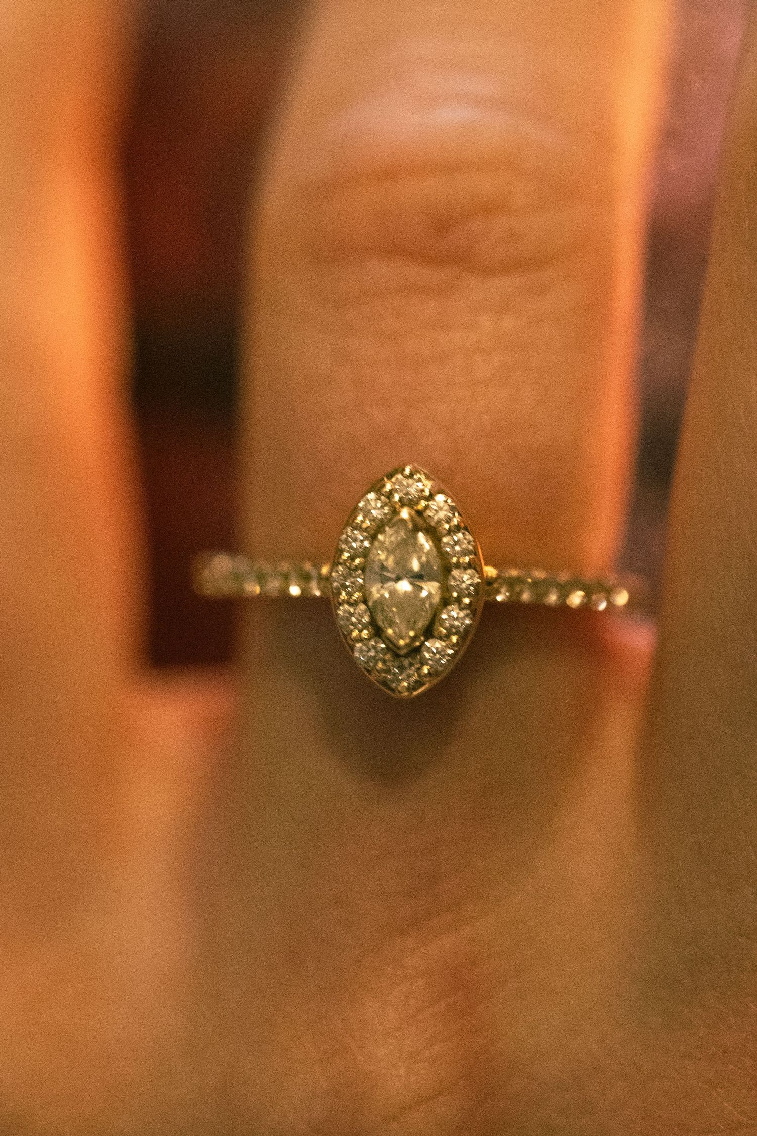 Gold halo engagement ring featuring a marquise diamond center stone surrounded by pavé diamonds on a delicate band.