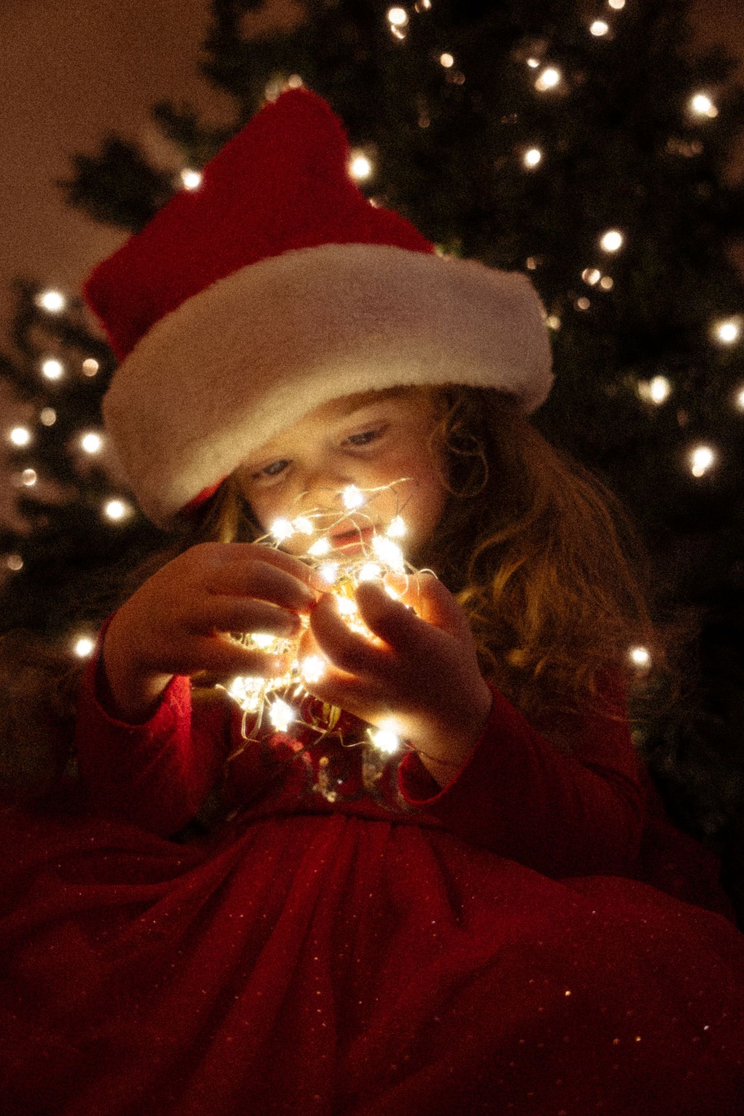 Christmas lights sparkle in the darkness against a red fabric background creating a magical holiday atmosphere.