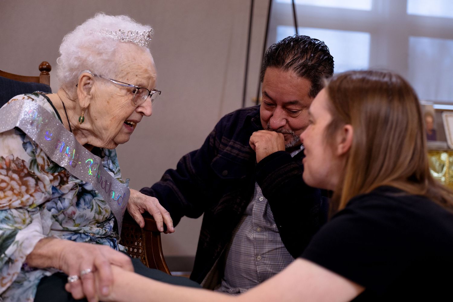 Three people share a joyful moment together while sitting at a table, engaged in lively conversation.