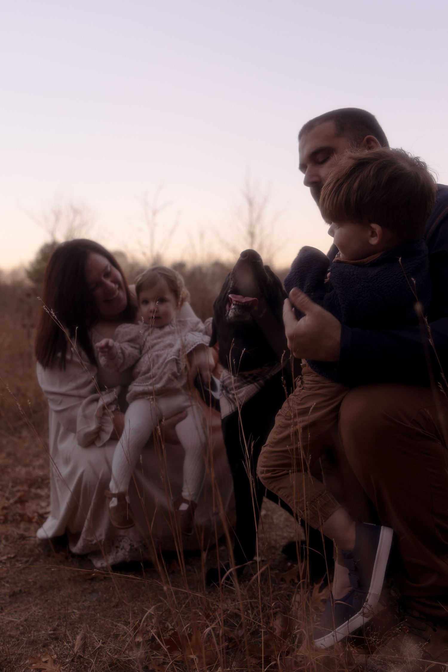 A group of people in white and brown clothing gather outdoors at dusk in a field.