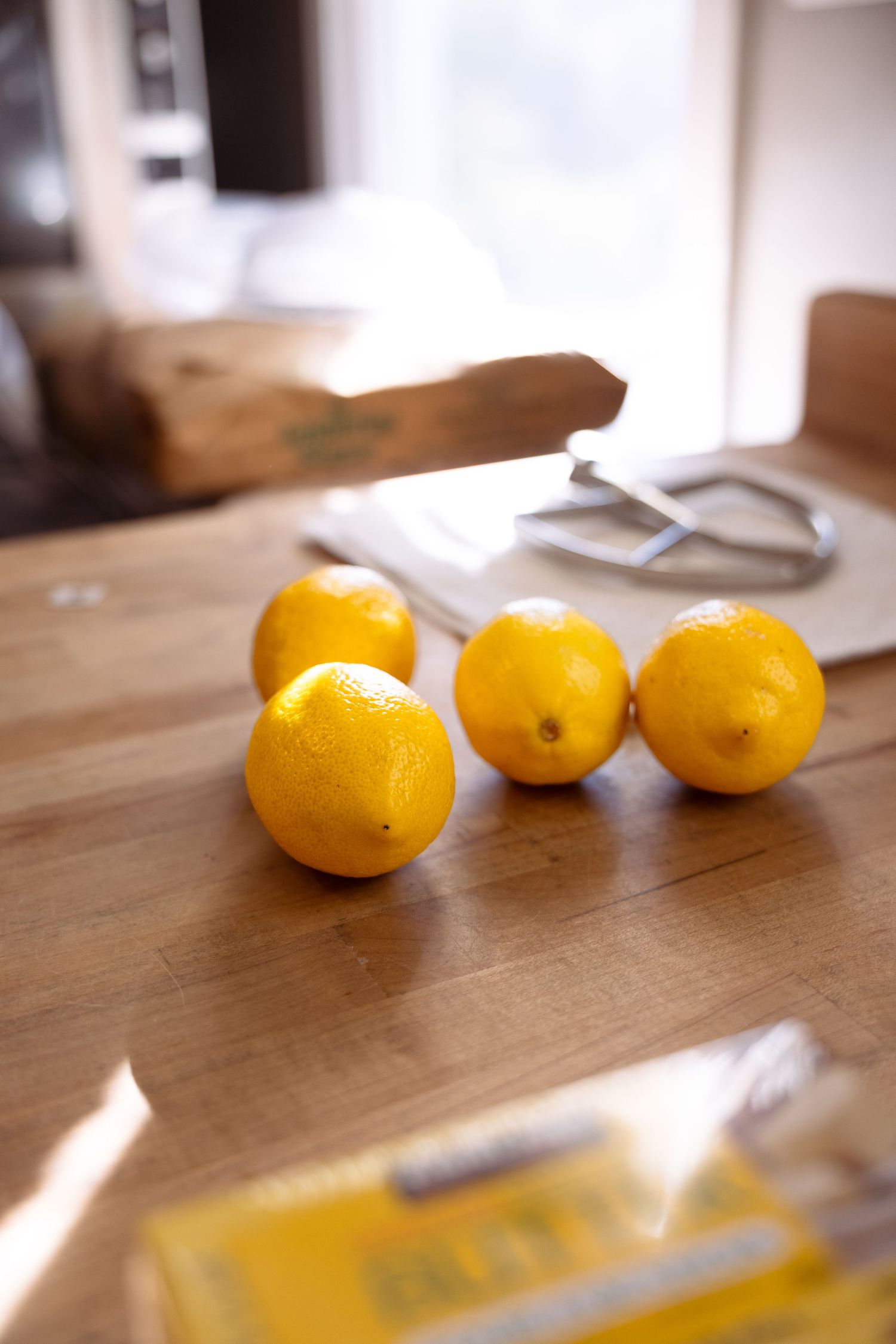 Fresh yellow lemons lined up on a wooden surface with natural lighting casting shadows.