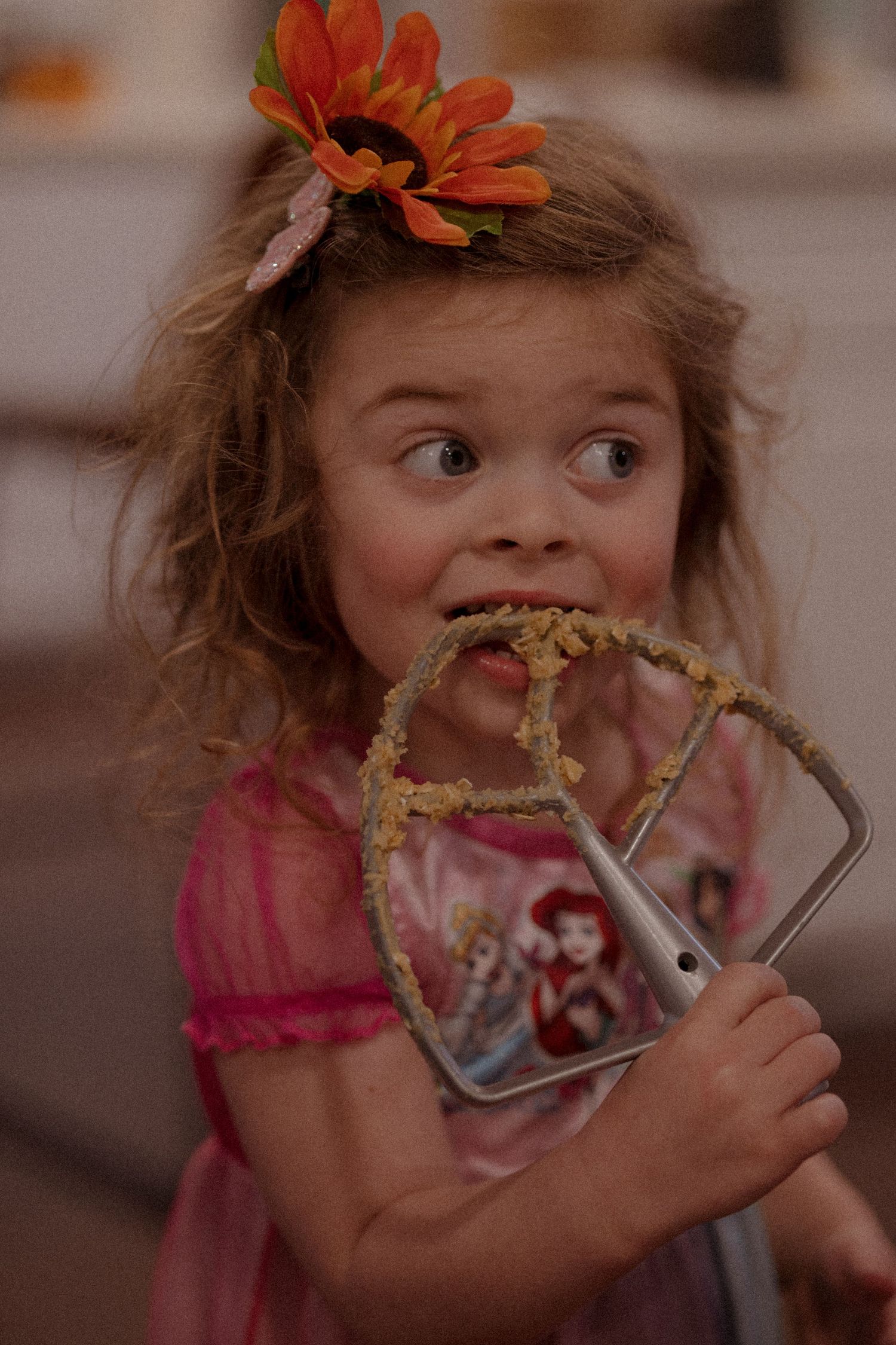 A child in a pink dress makes silly faces while eating messy food in a sequence of candid photos.