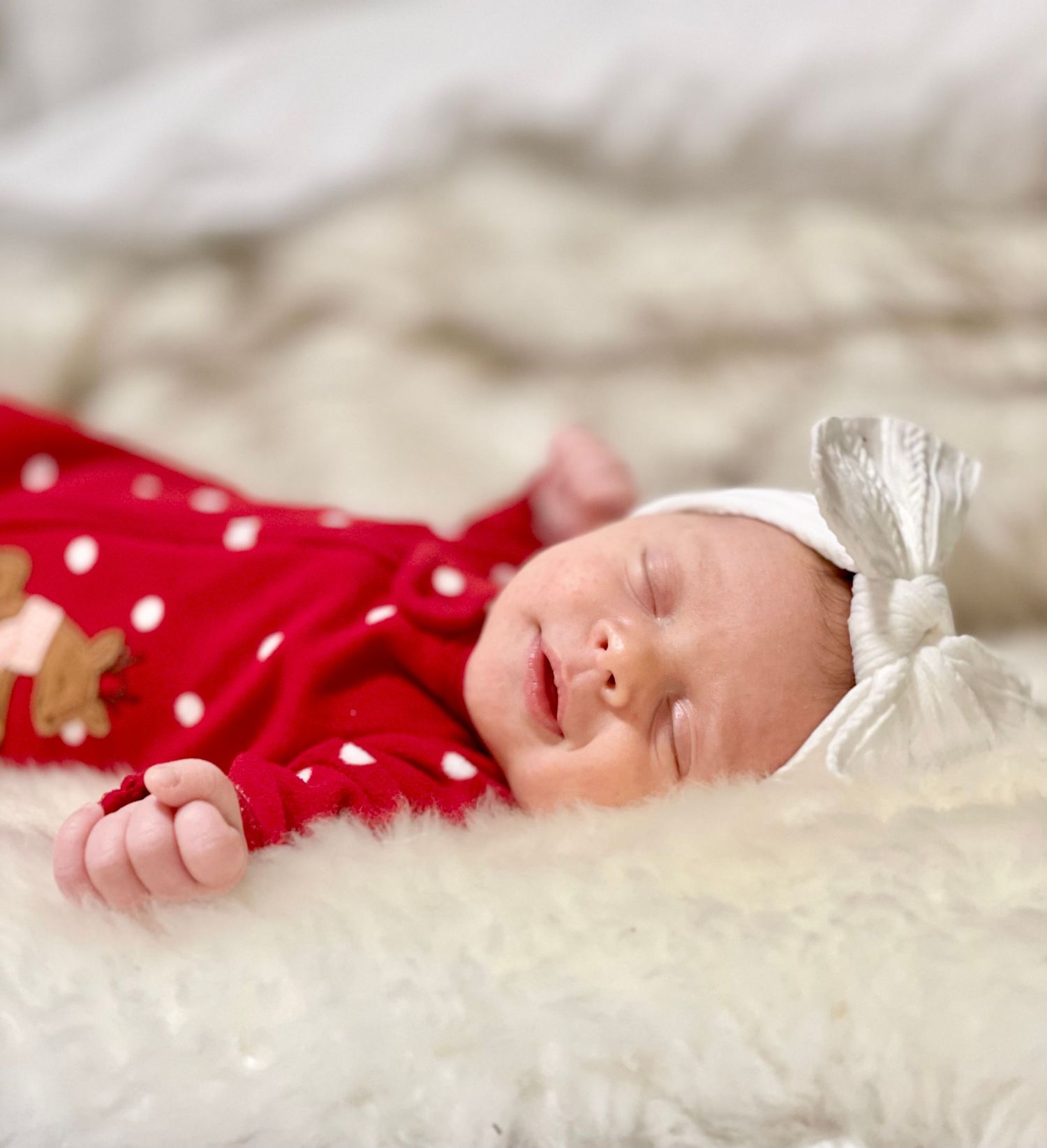 Local Westfield family photographer portrait of A sleeping newborn baby wrapped in white fabric against soft textured bedding.