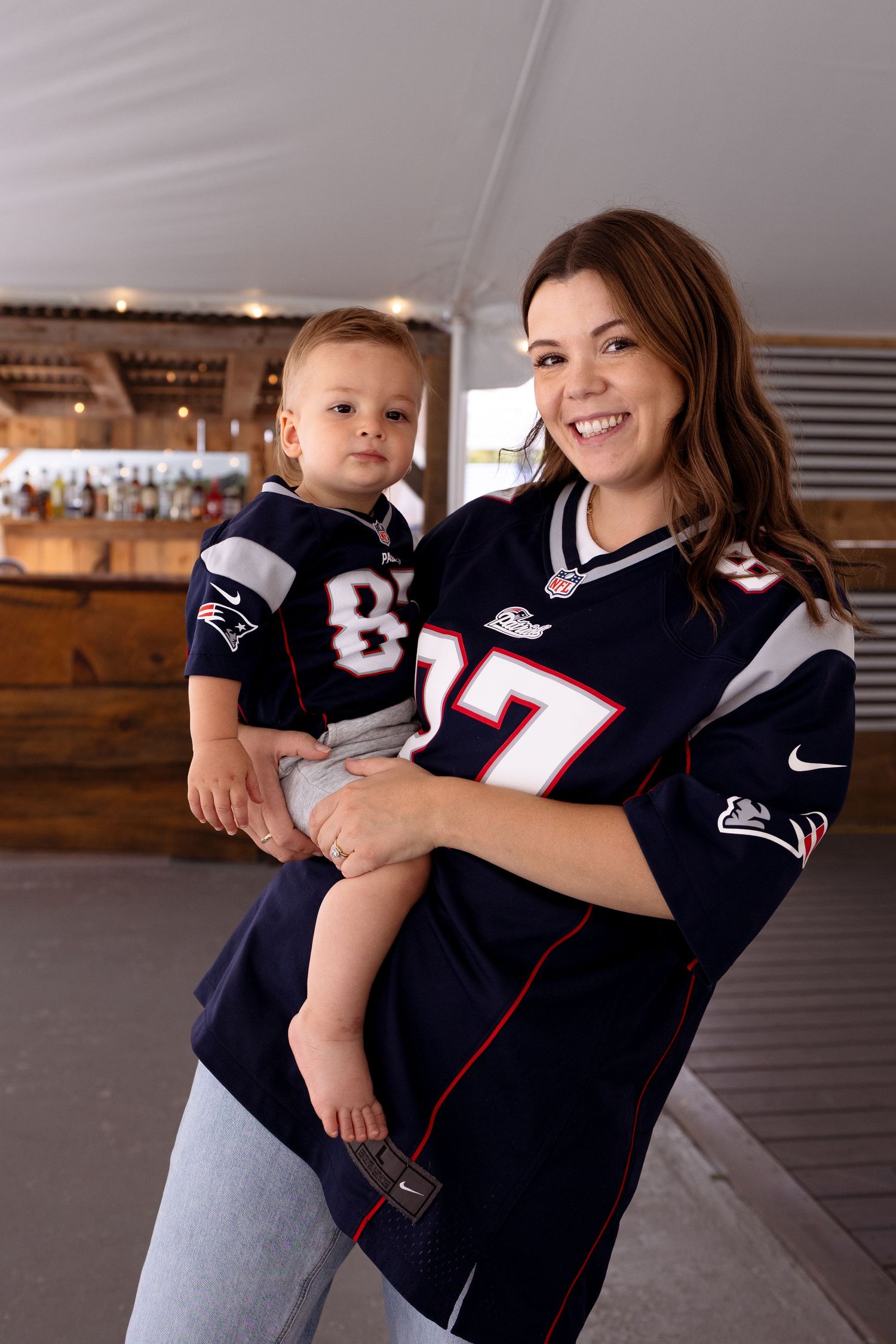 Two people wearing New England Patriots jerseys pose together in a series of casual shots.