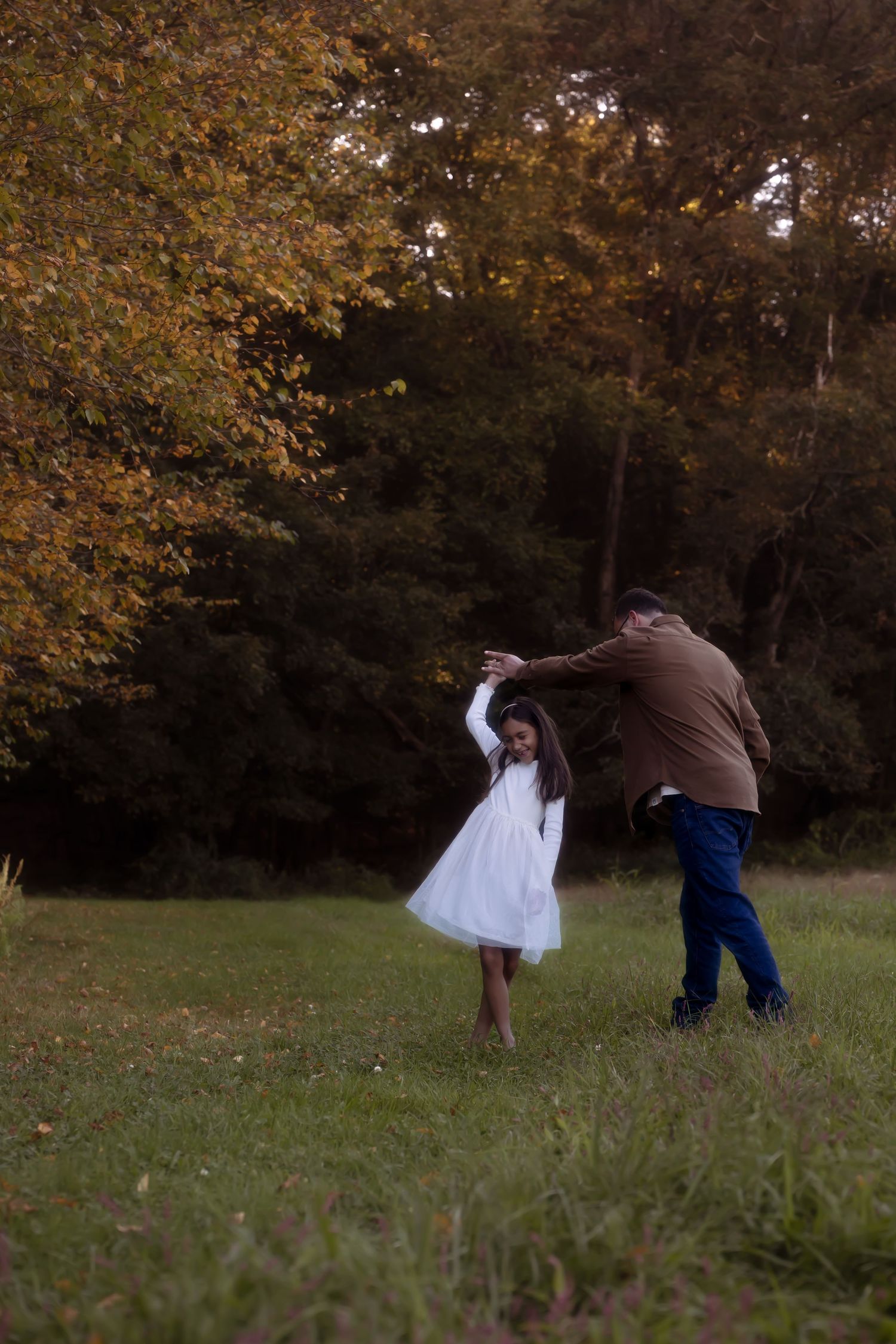 A sequence of images showing people falling in a grassy field during autumn with golden leaves on trees in the background.