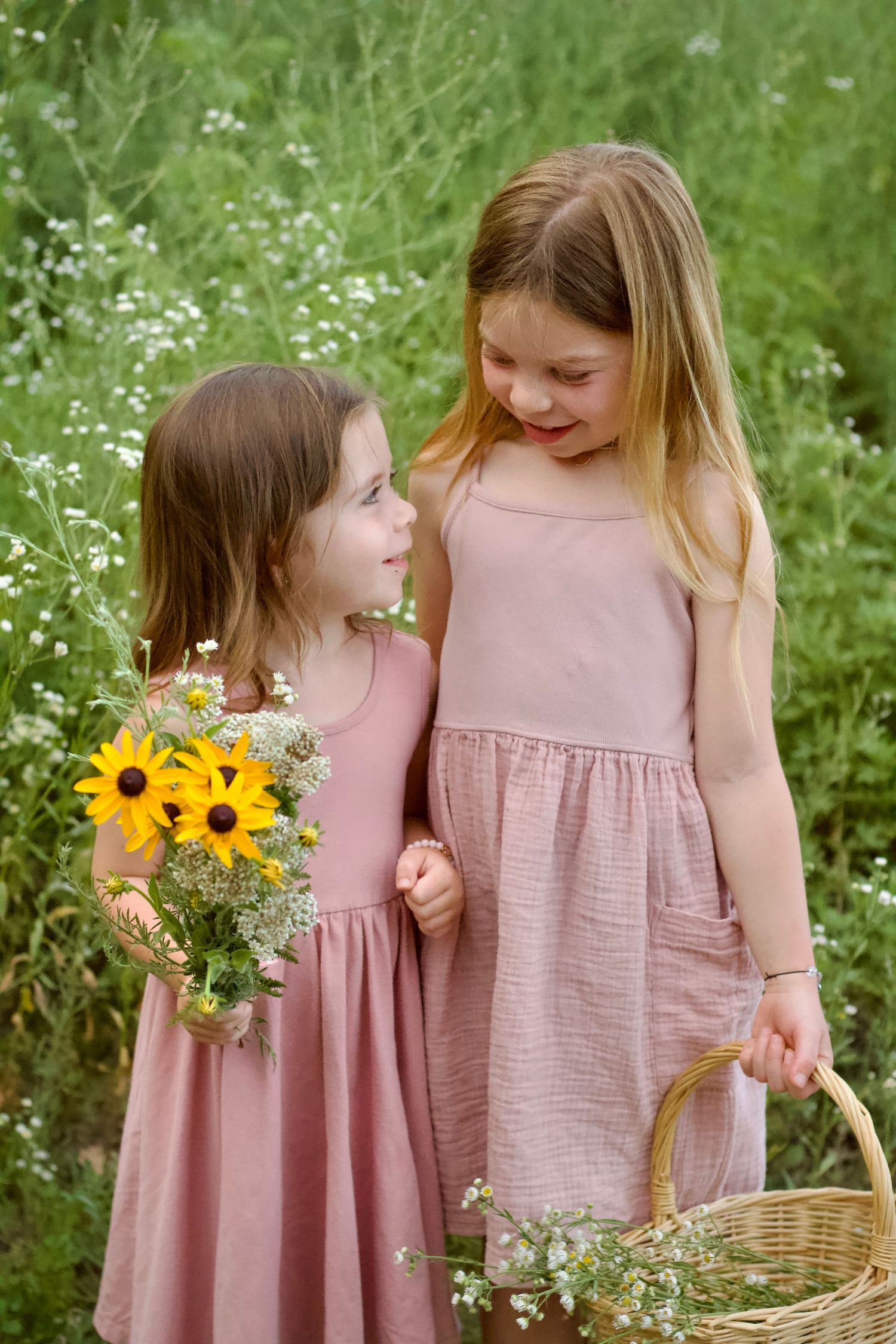 local Westfield family photographer photo of young girls in matching pink dresses holding wildflower bouquet and rustic farm basket