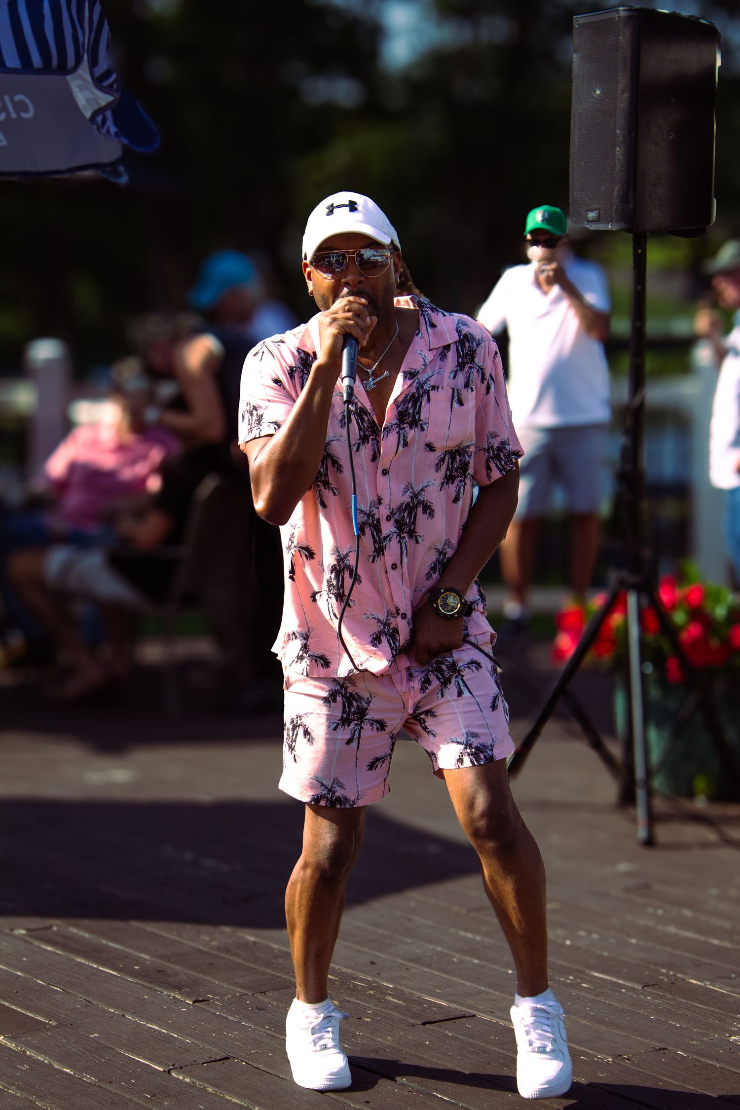 Motion sequence showing someone in a pink floral shirt and white shoes dancing outdoors in summer.