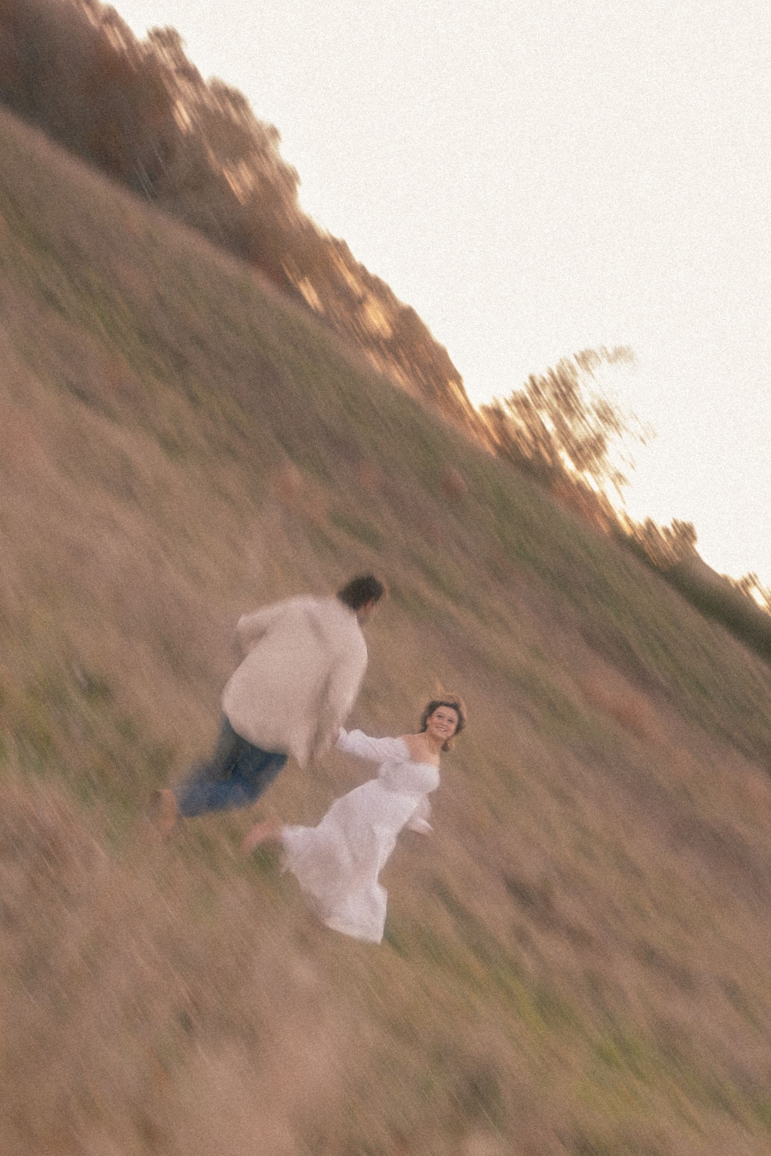 A sequence of photos shows a person in white clothing rolling down a grassy hillside at sunset.