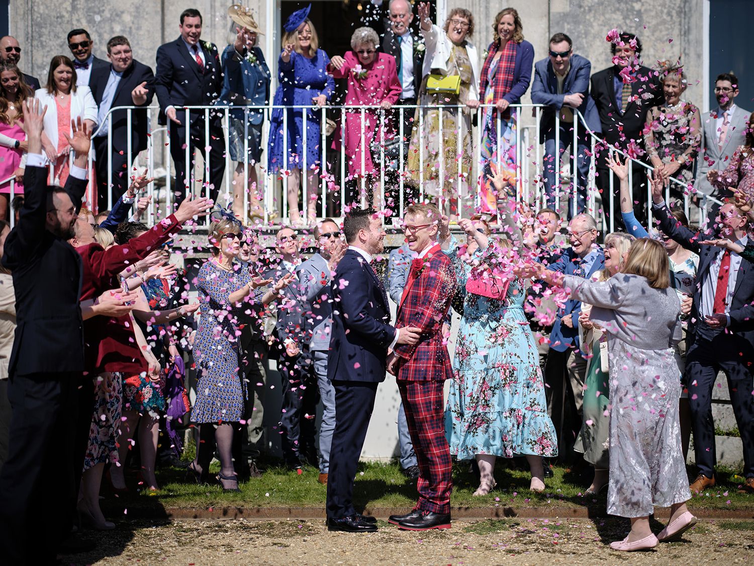 Wedding guests throw colorful confetti over a couple while others watch from a balcony at Kinston Maurward.