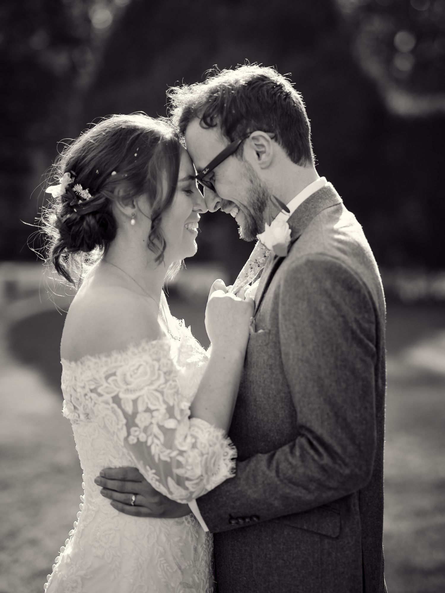A romantic black and white wedding portrait of a couple sharing an intimate moment in their formal attire.
