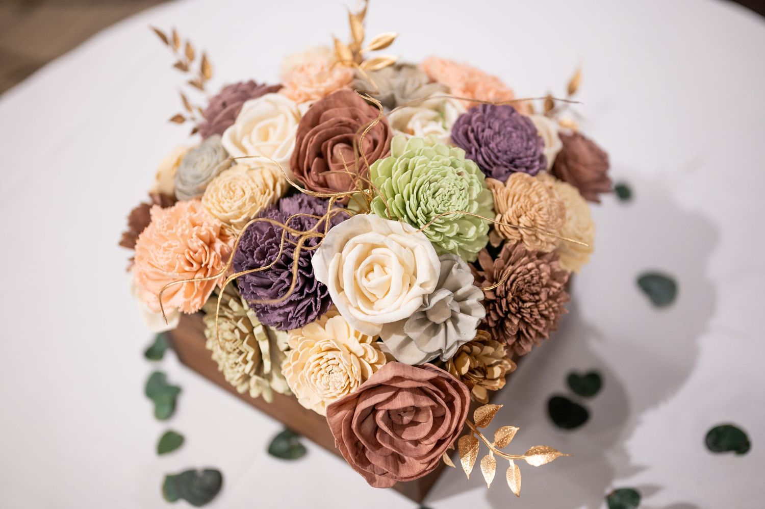 A beautiful wedding bouquet with roses in muted peach, purple and green tones.