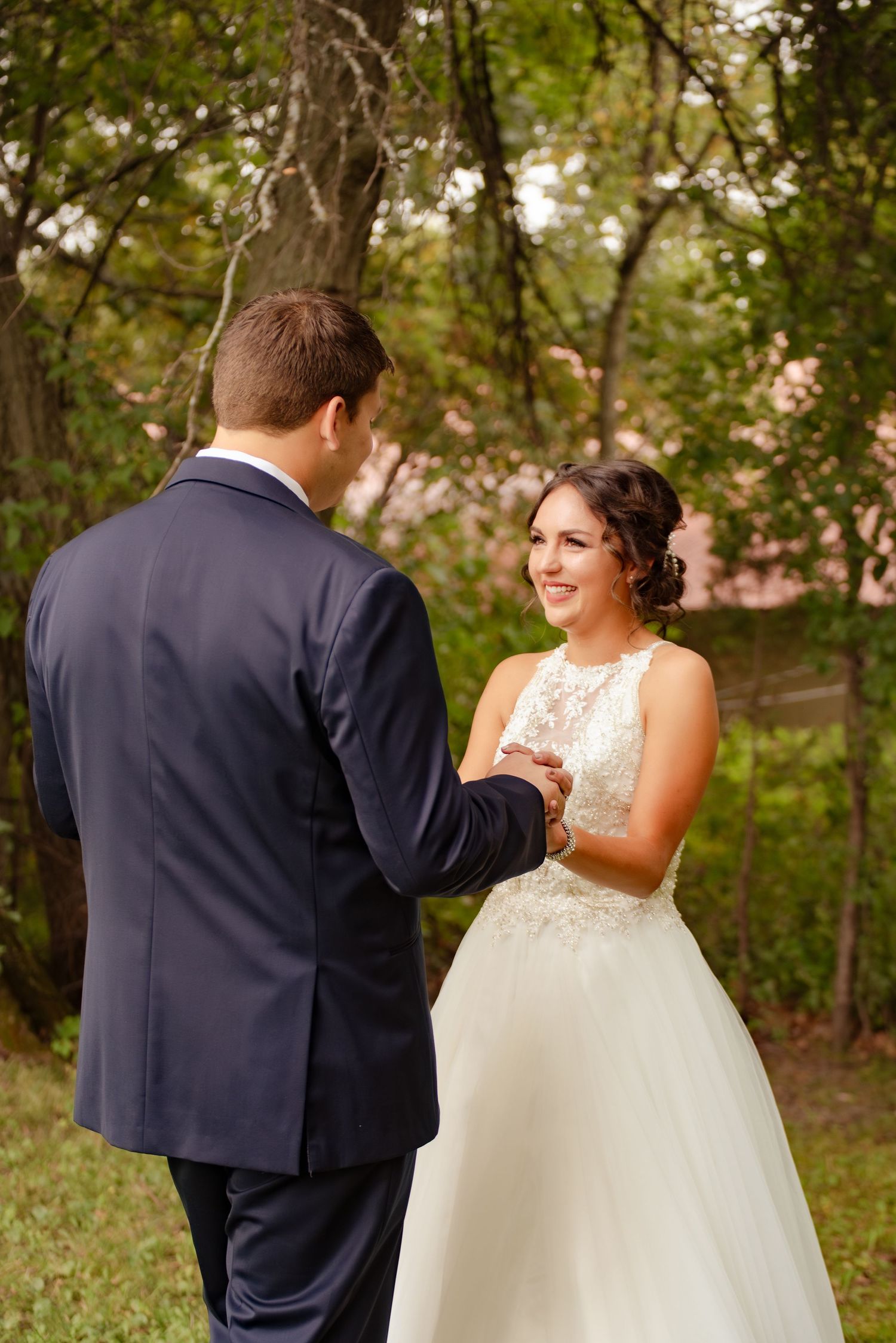 Joyful wedding moment captured outdoors as couple exchanges rings in formal attire.
