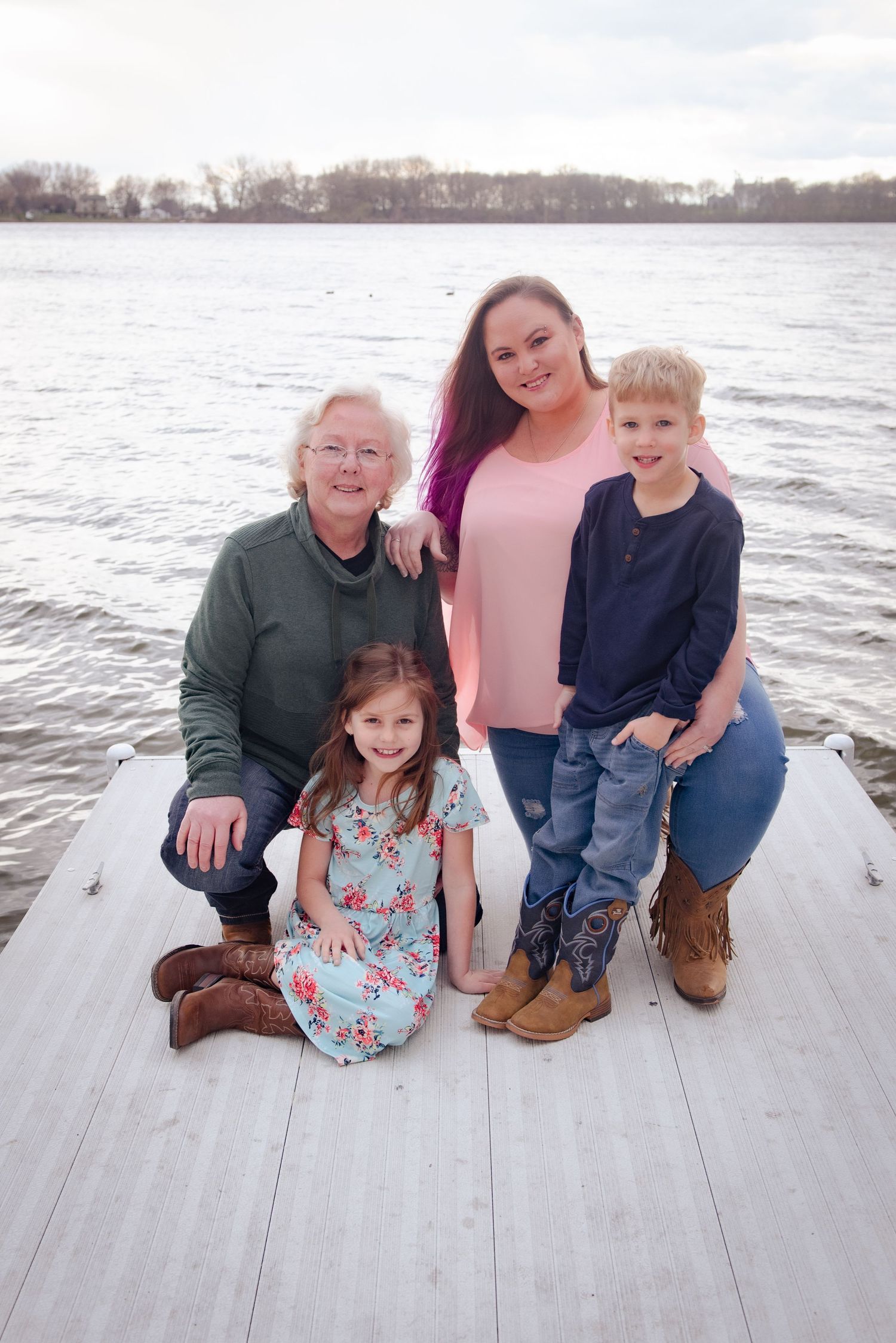 Multi-generational family portrait on a dock with a lake and trees in background.