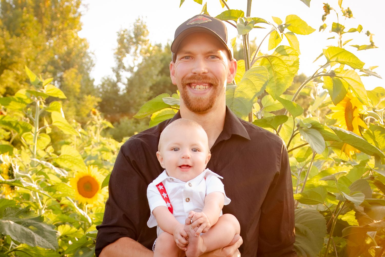 Tender outdoor portrait in a sunflower garden during golden hour.