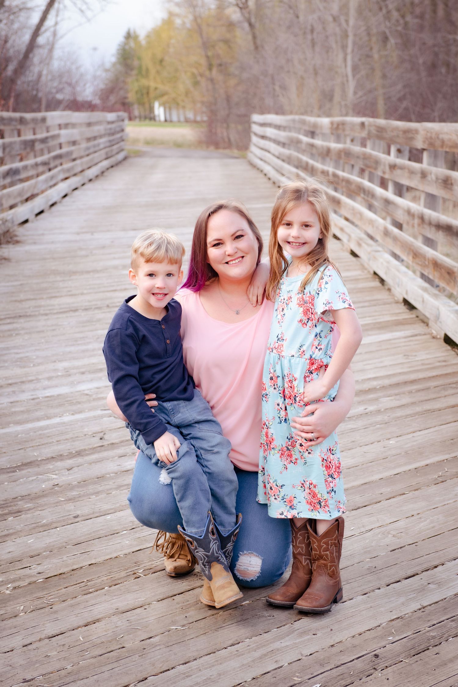 A family portrait taken on a wooden boardwalk surrounded by autumn trees.