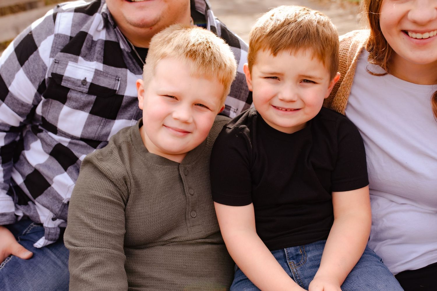 Close up of family sitting together and smiling on wooden bridge.