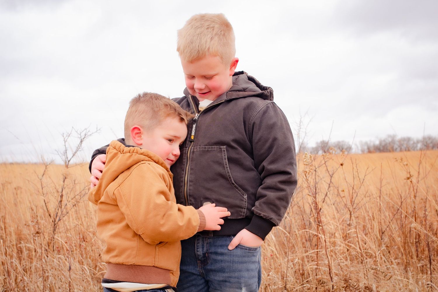 Two children sharing moment together in tall grass field.