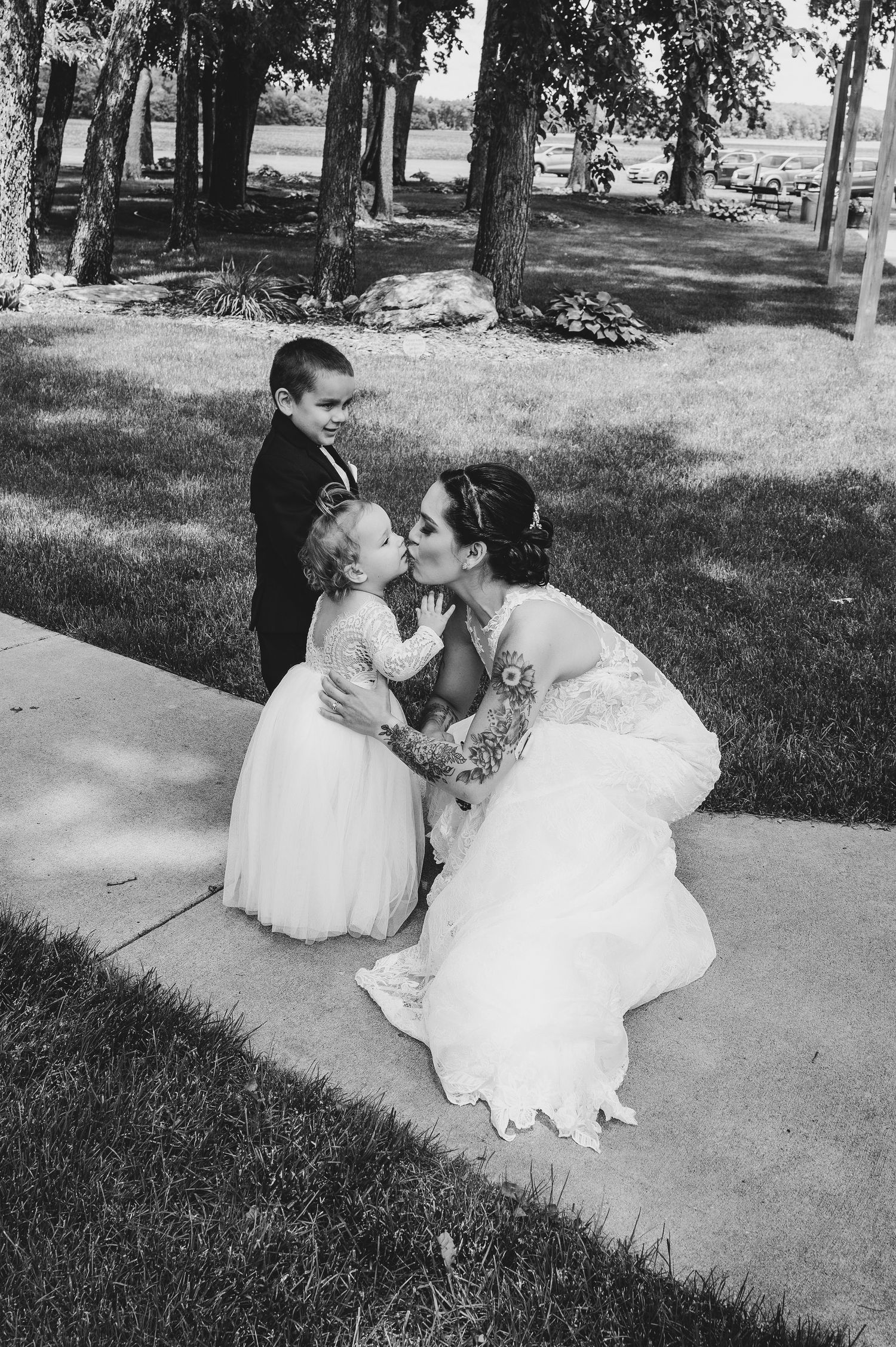 Black and white portrait of tender wedding moment on outdoor pathway.