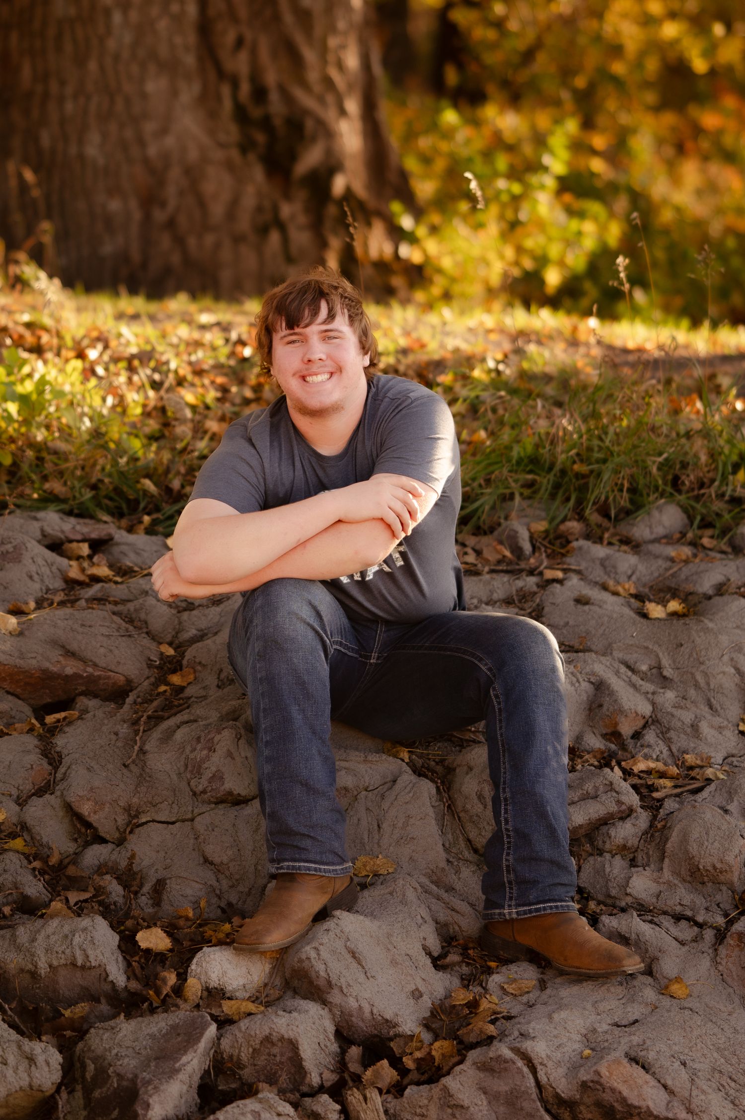 Person sitting on rocky terrain wearing casual attire during autumn golden hour.