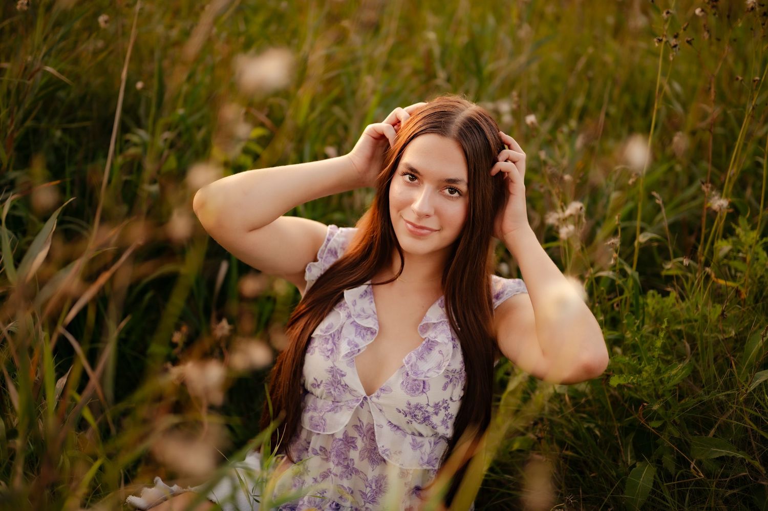 Outdoor portraits in warm sunlight featuring someone in a floral dress posing among tall grass and wildflowers.