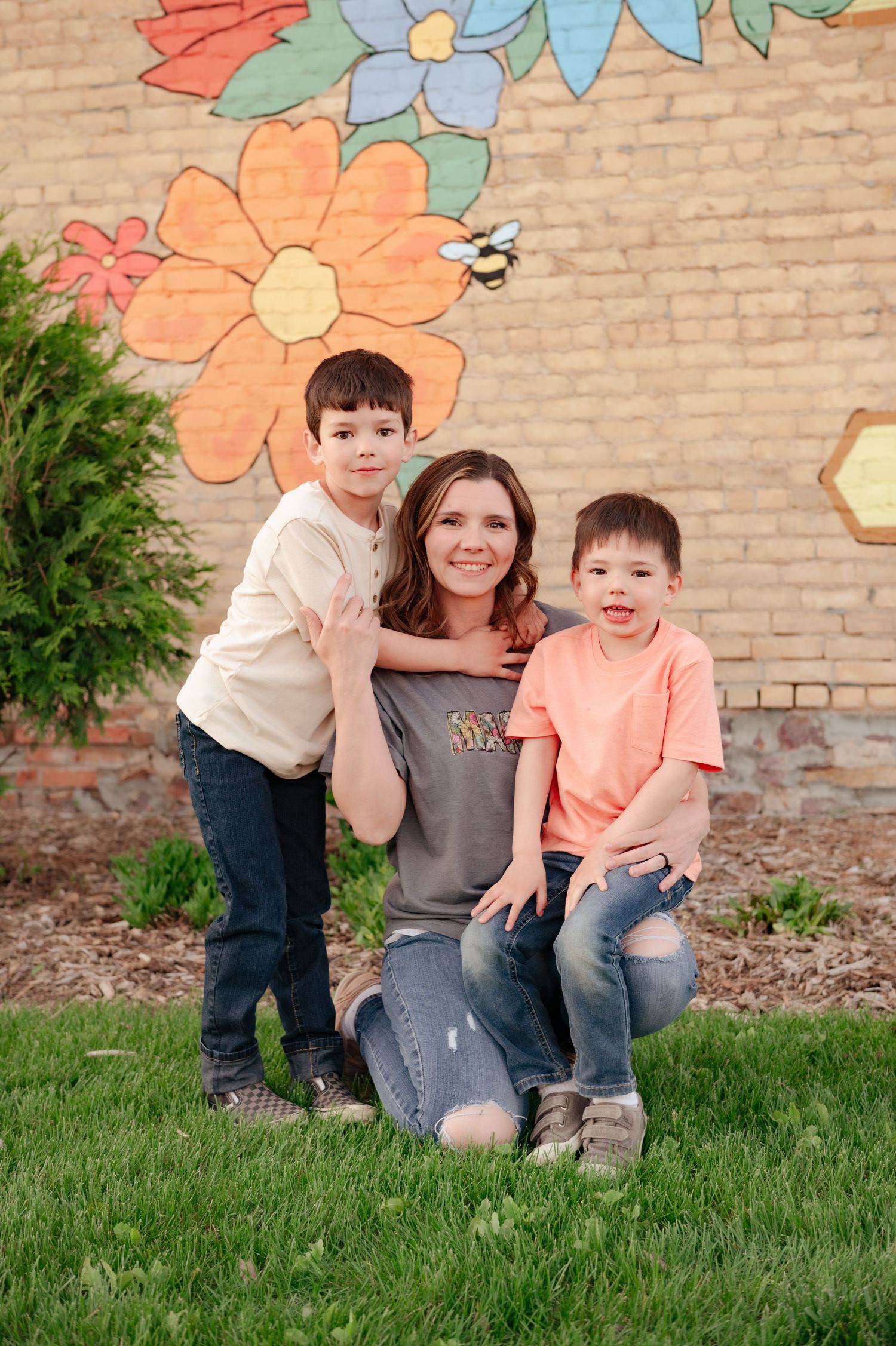 Cheerful family photo against decorative brick wall with painted flowers.