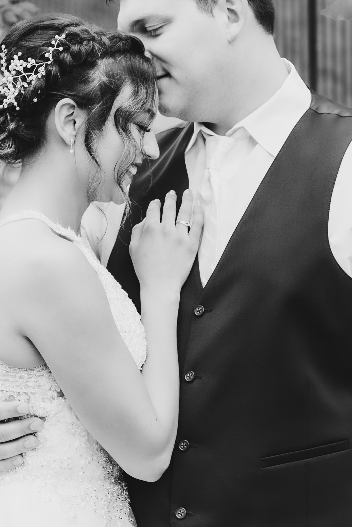 Black and white intimate portrait of newlyweds in formal wedding attire.