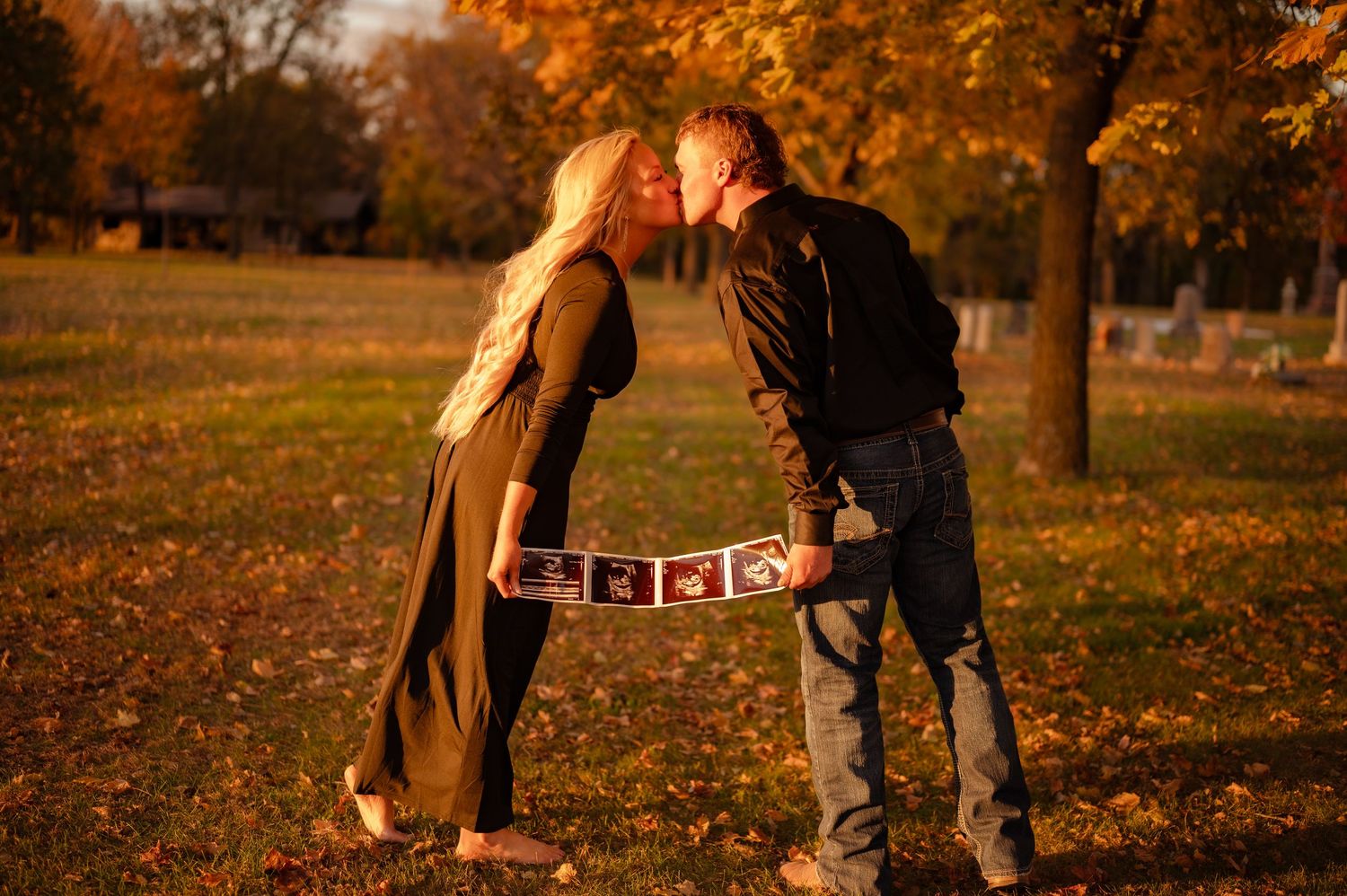 Couple sharing intimate moment in autumn park with golden foliage at sunset.