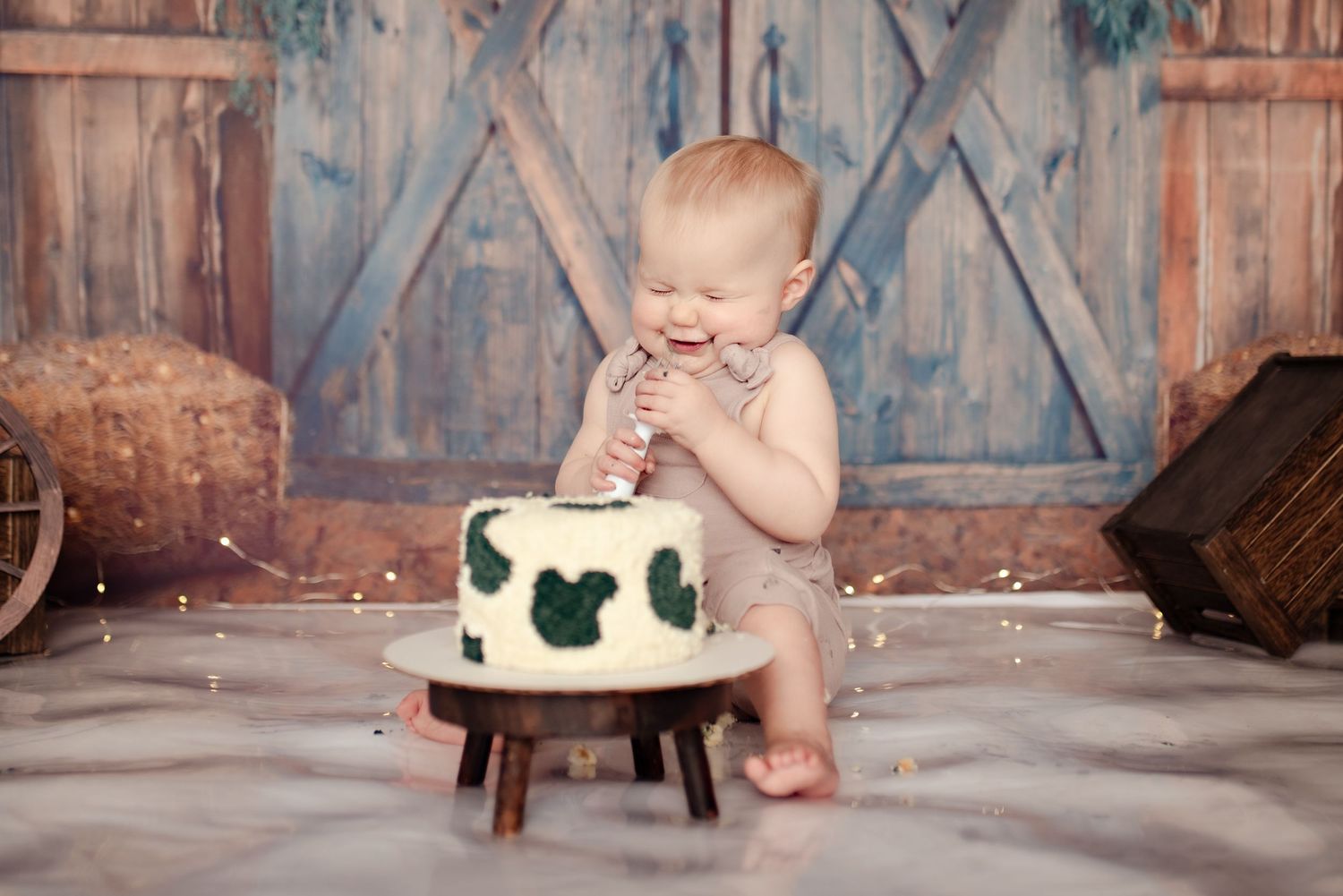 Excited baby reaching for white cake with Mickey Mouse decorations on wooden stand.