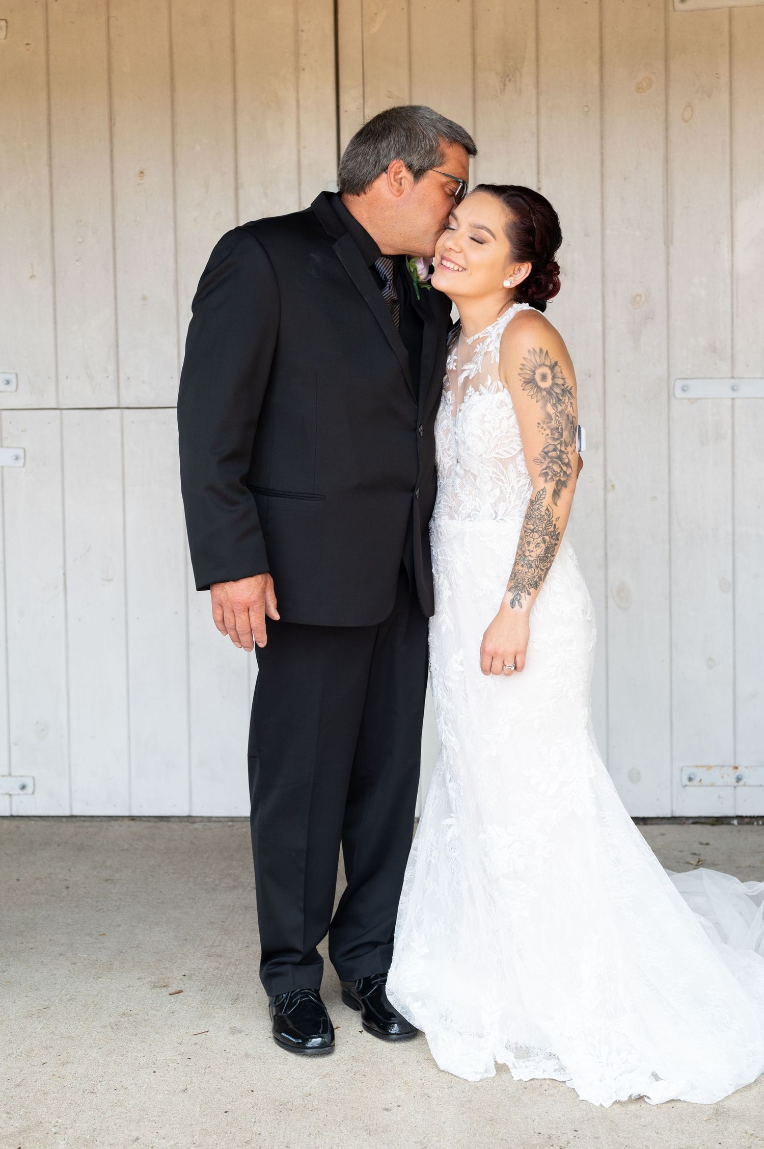 A tender wedding moment captured against a rustic wooden door backdrop.