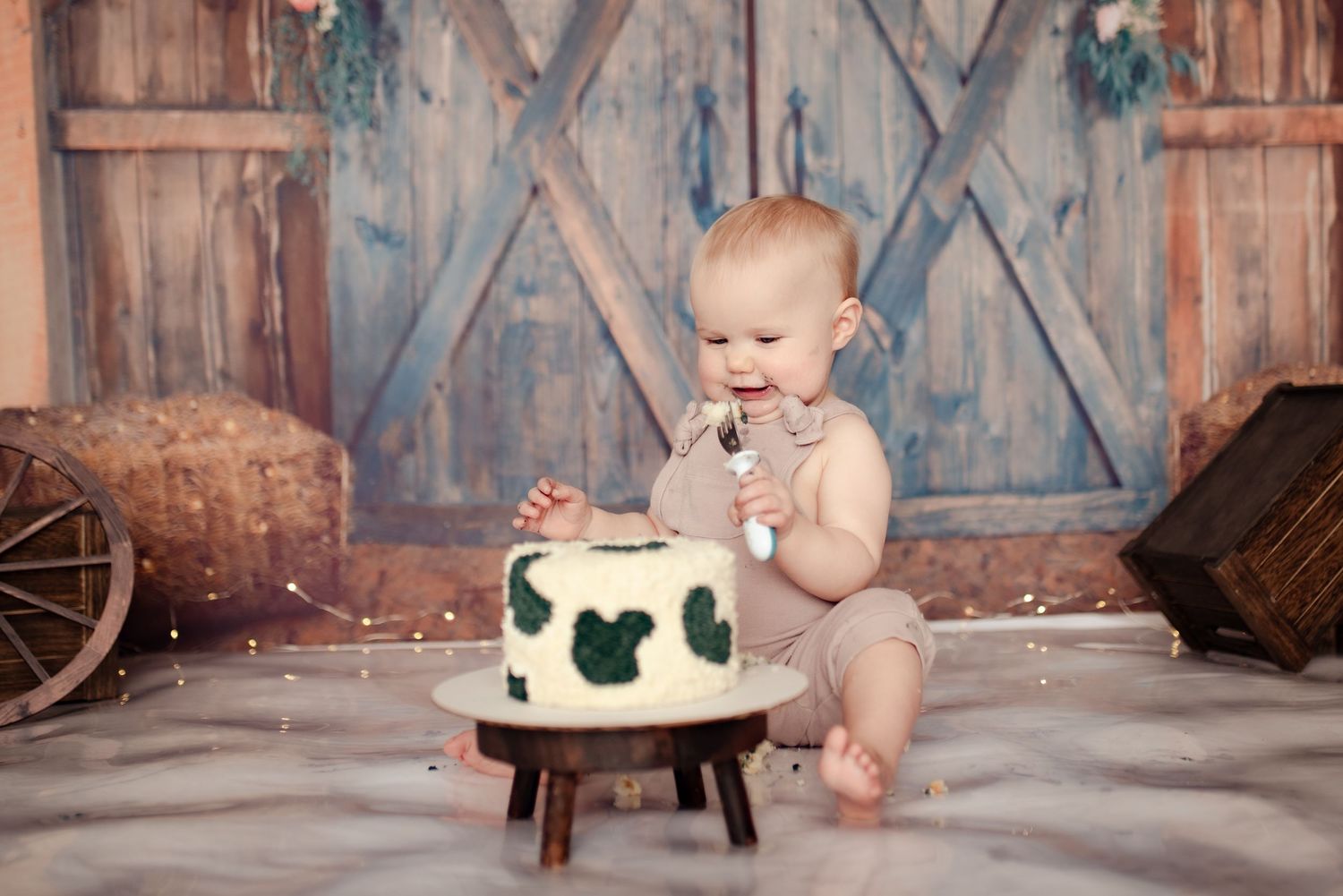 Baby reaching for small white cake decorated with Mickey Mouse designs.