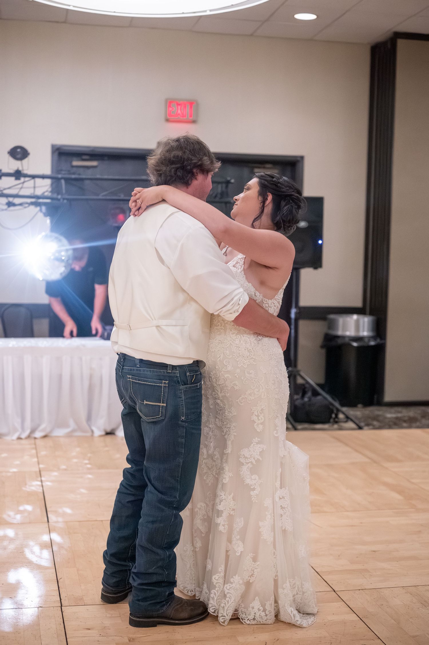 A couple shares their first dance at a wedding reception in a banquet hall.