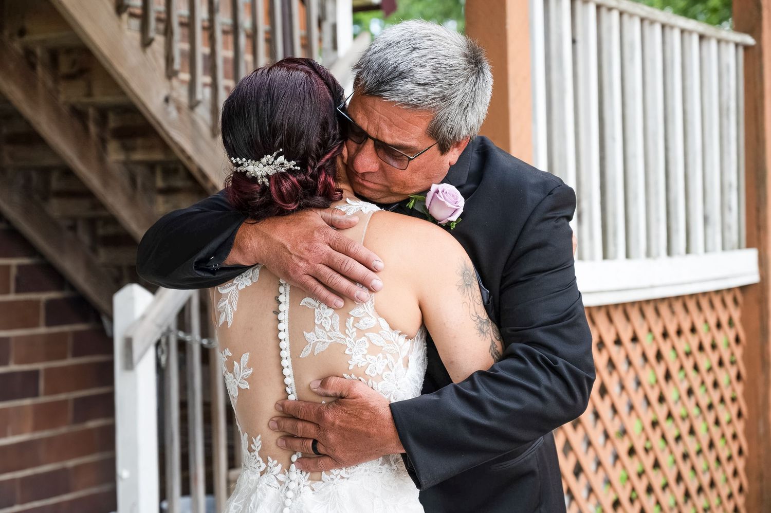 An emotional embrace captured during a wedding against a white wooden backdrop.