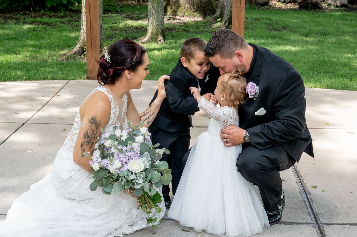 Wedding party sharing intimate moment under wooden pavilion.