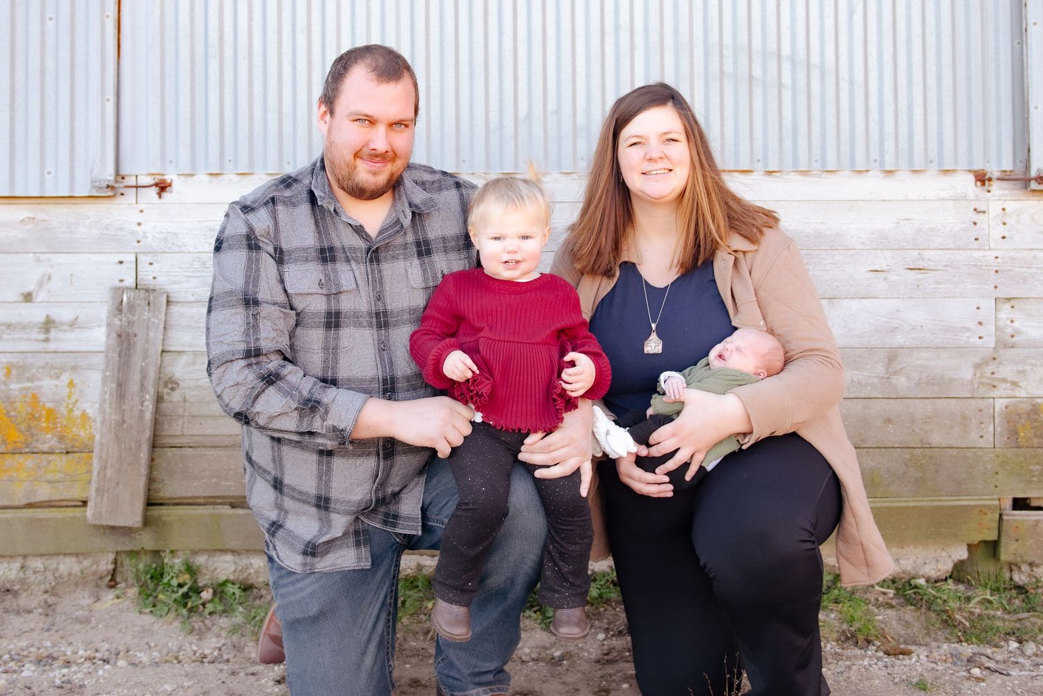 Family portrait against rustic wall with casual attire.