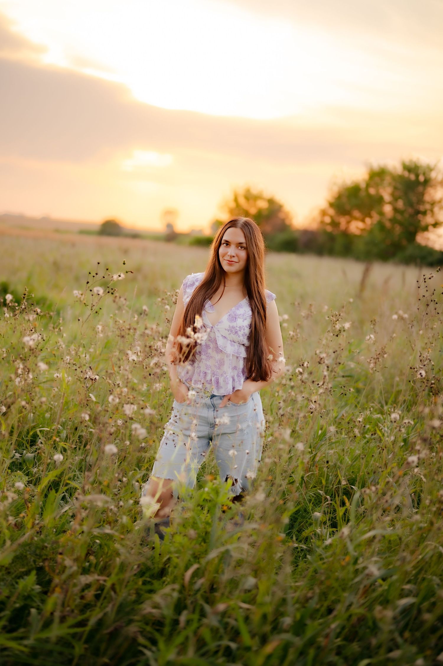 A person stands in a blooming wildflower meadow at sunset with golden light illuminating the peaceful scene.