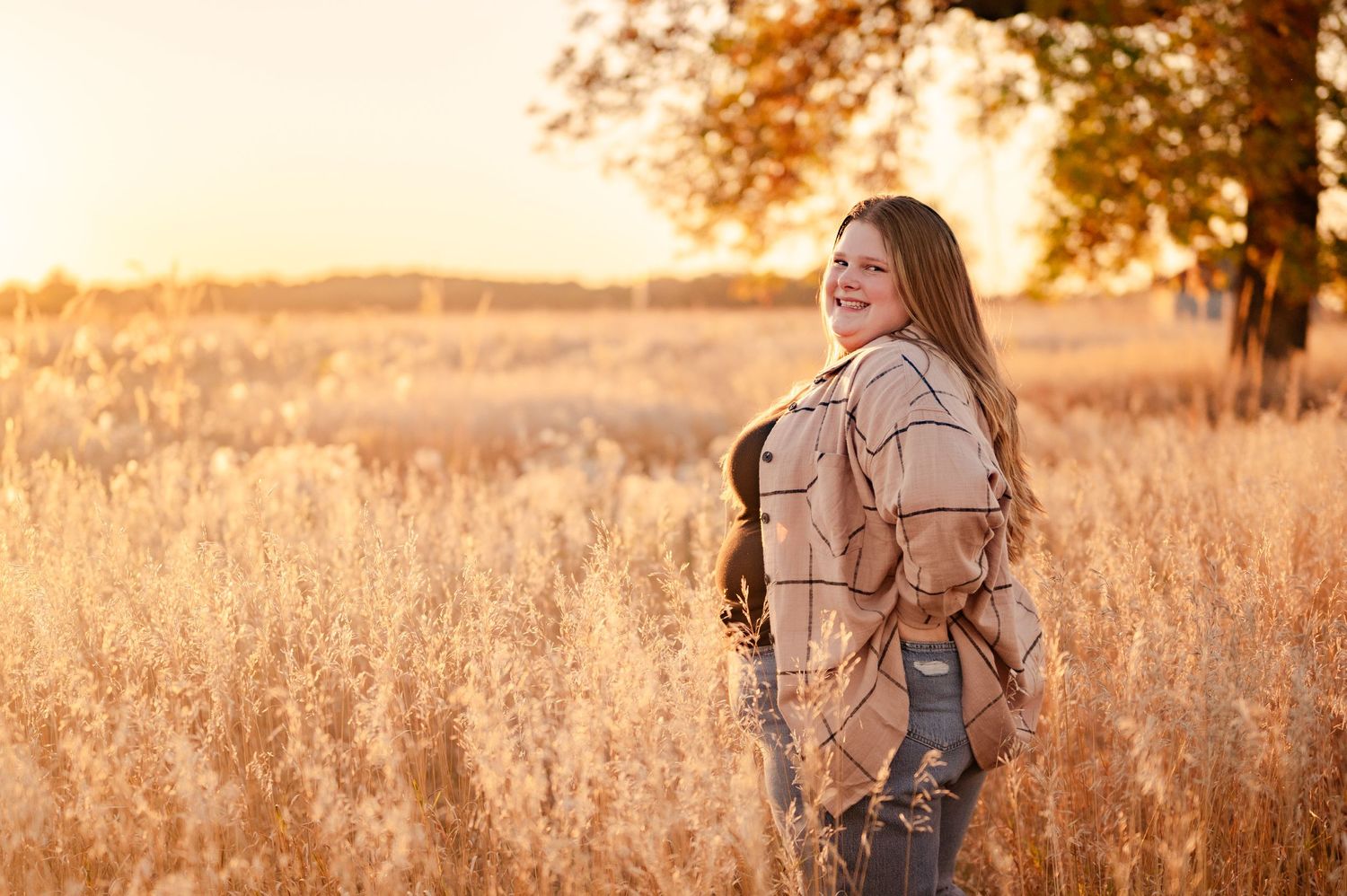 A stylish autumn portrait in a wheat field during golden hour sunset.