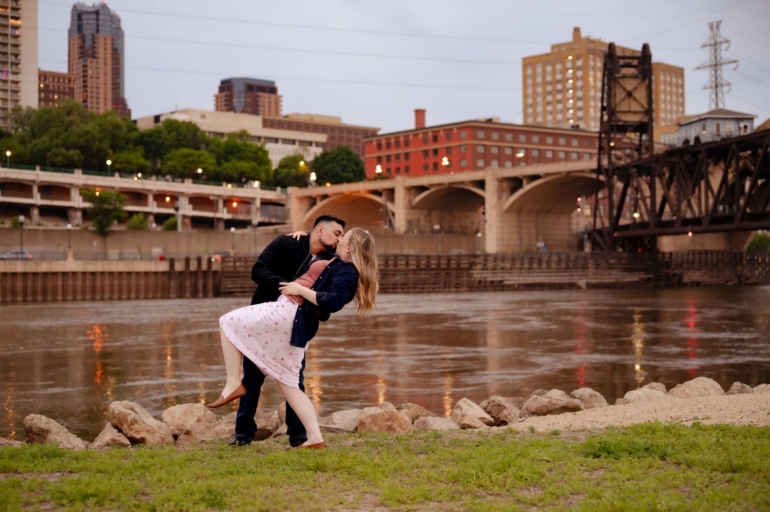 A romantic couple poses along the Mississippi riverfront in Minneapolis during an engagement photo session.