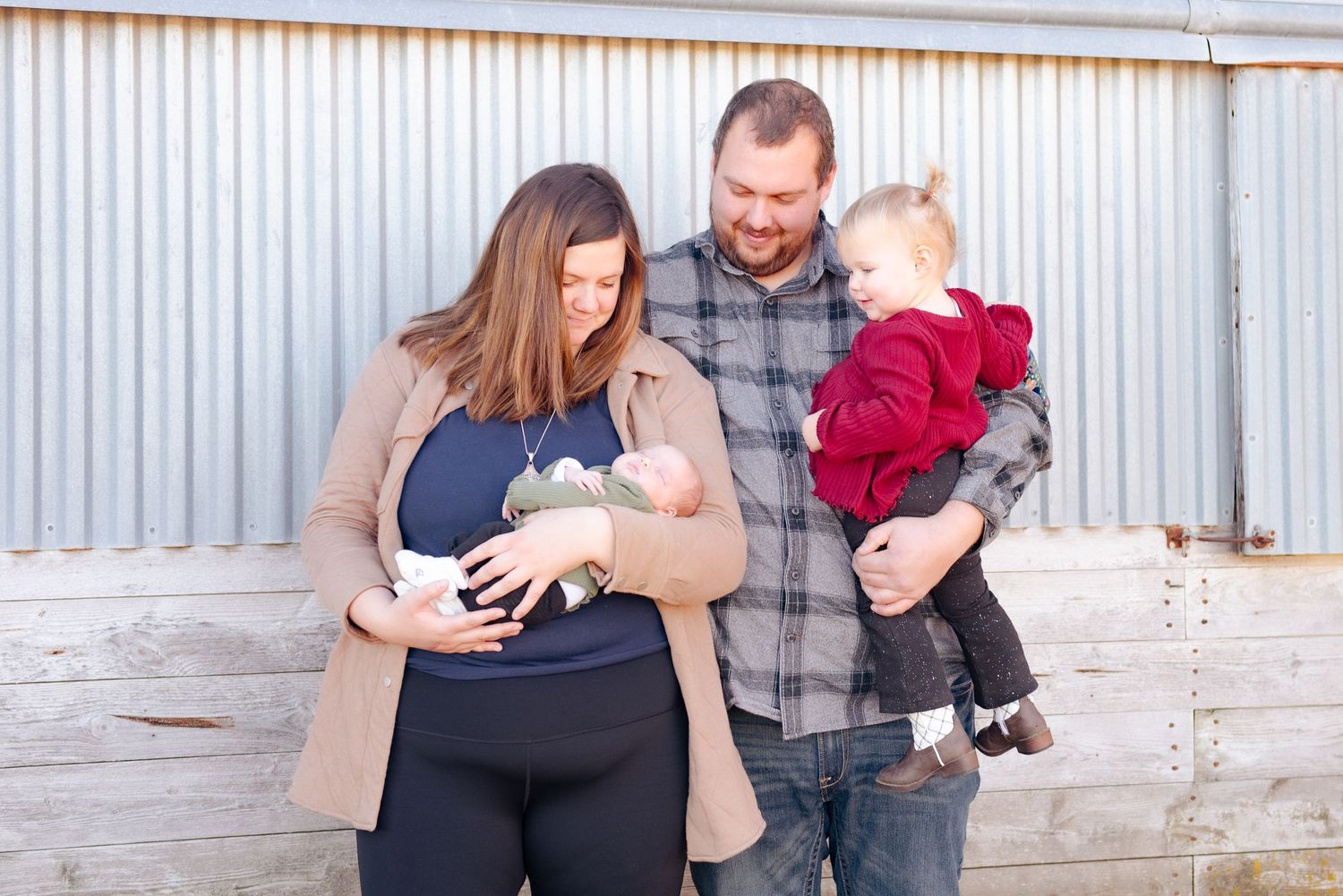 Family portrait outdoors against a corrugated metal wall.