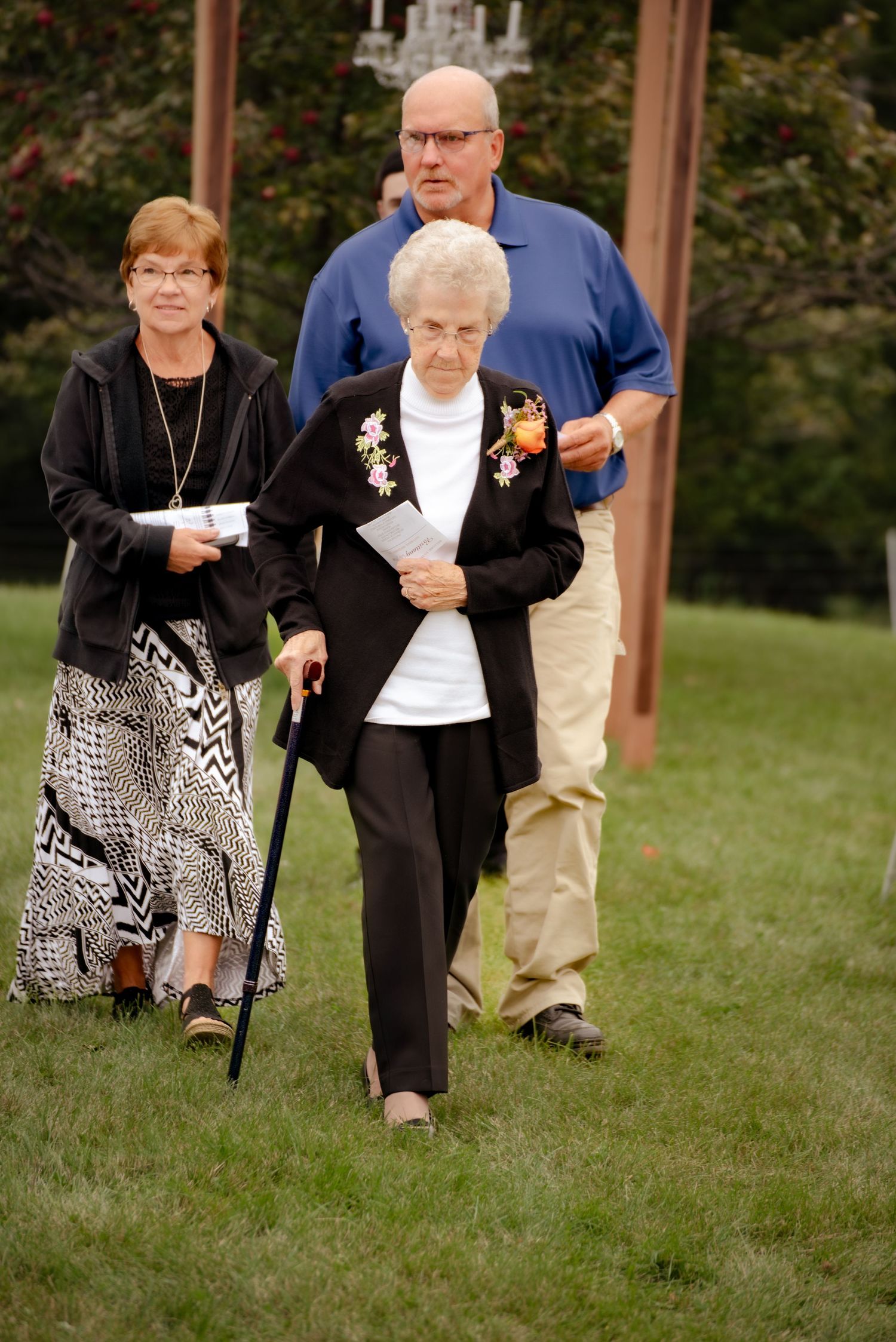 Wedding guests walking across a grassy lawn during an outdoor ceremony.