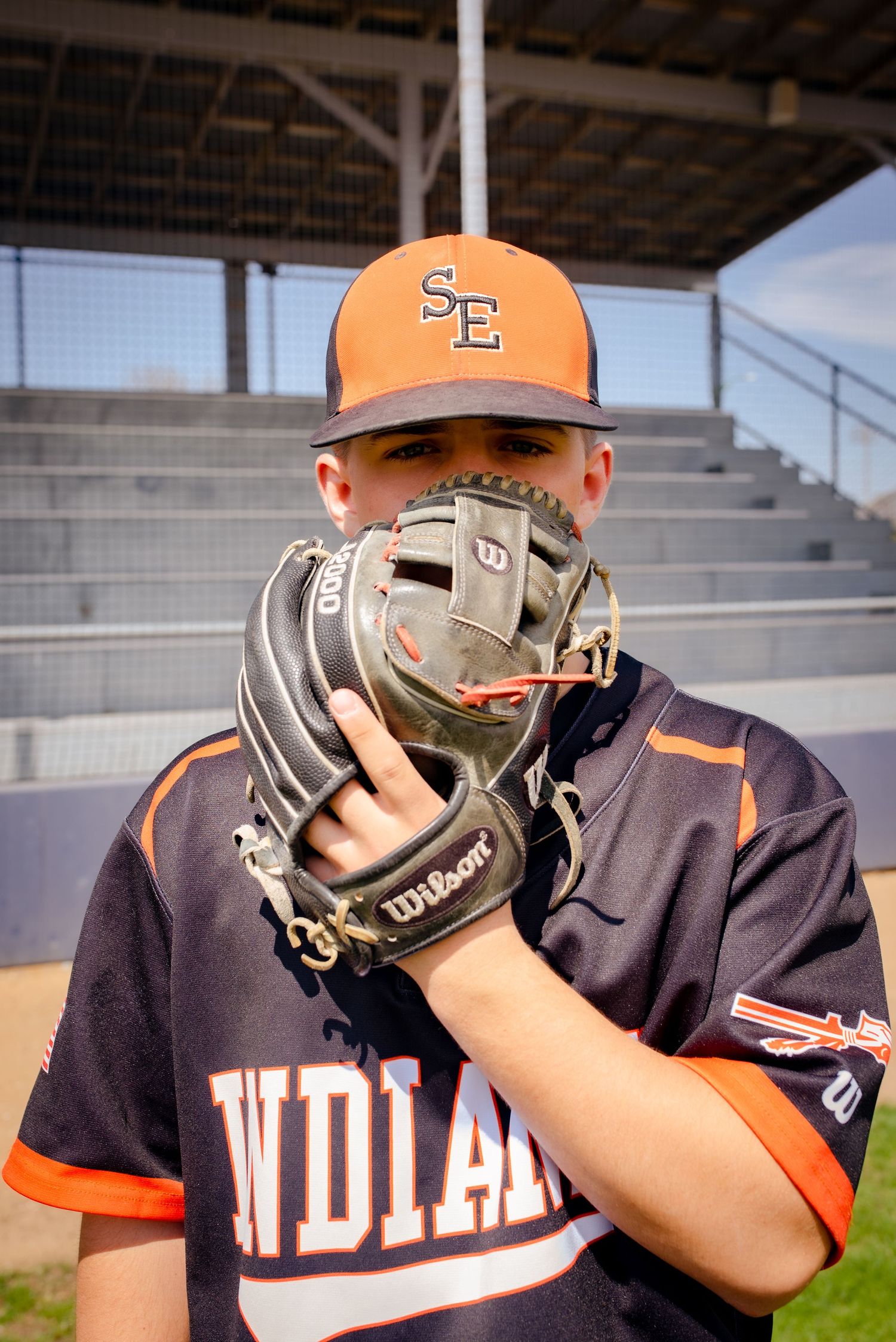 Baseball player in Indians uniform holds glove up to face during team photo.