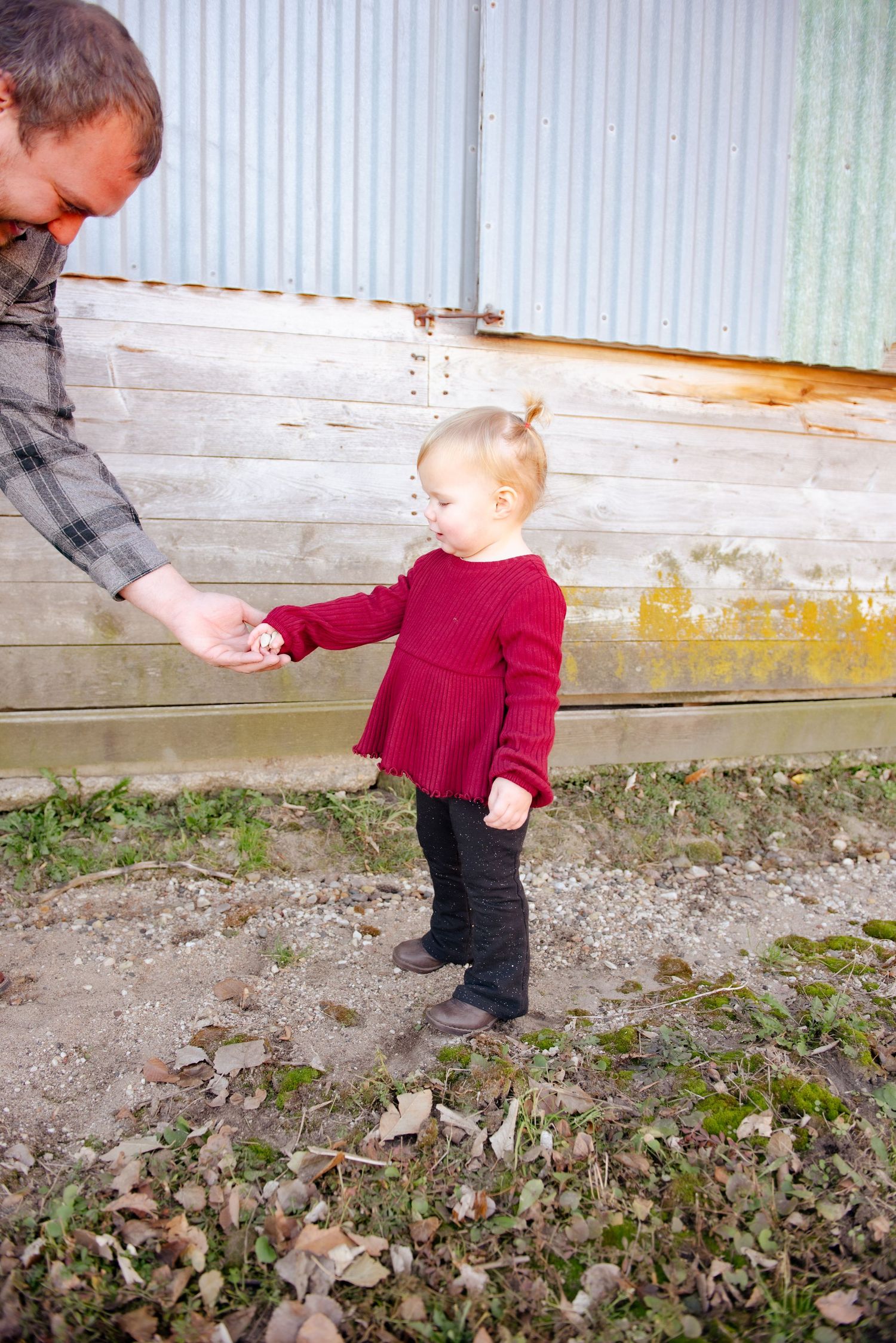 A touching moment between two people holding hands against a weathered wall backdrop.